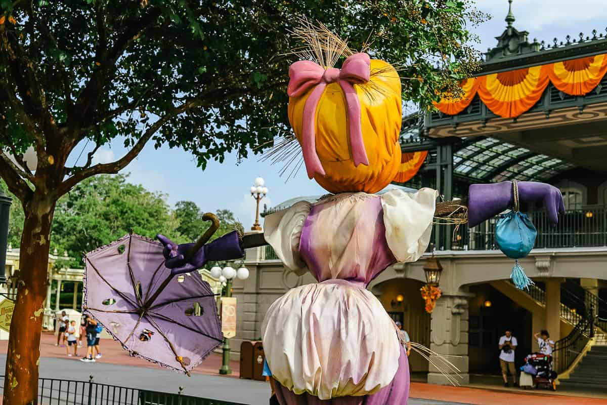 a purple scarecrow with a pink bow and purple umbrella 