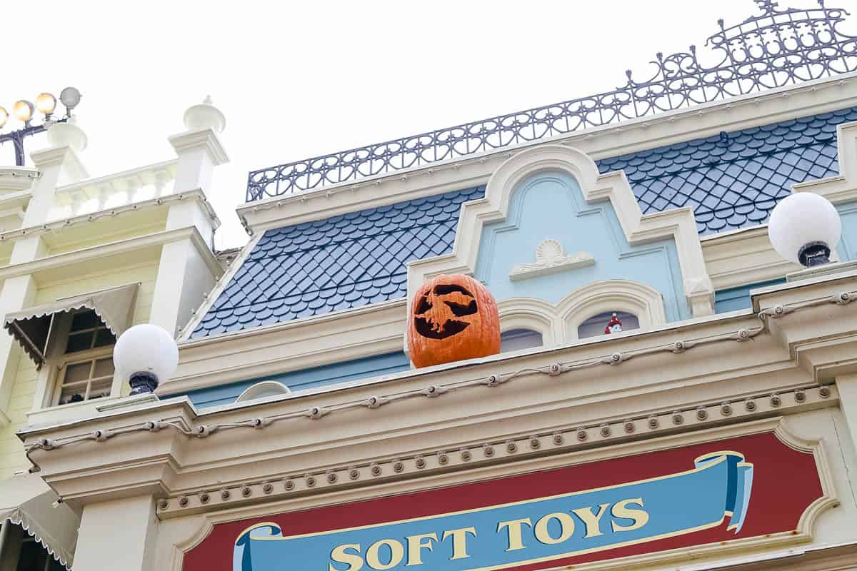 a witch carving pumpkin on Main Street USA 