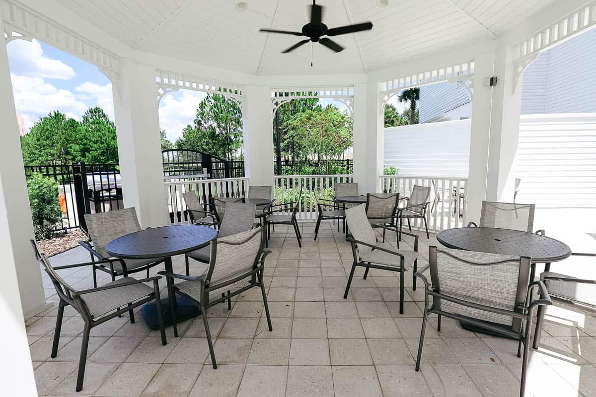 a covered pavilion near the pool with tables and chairs 