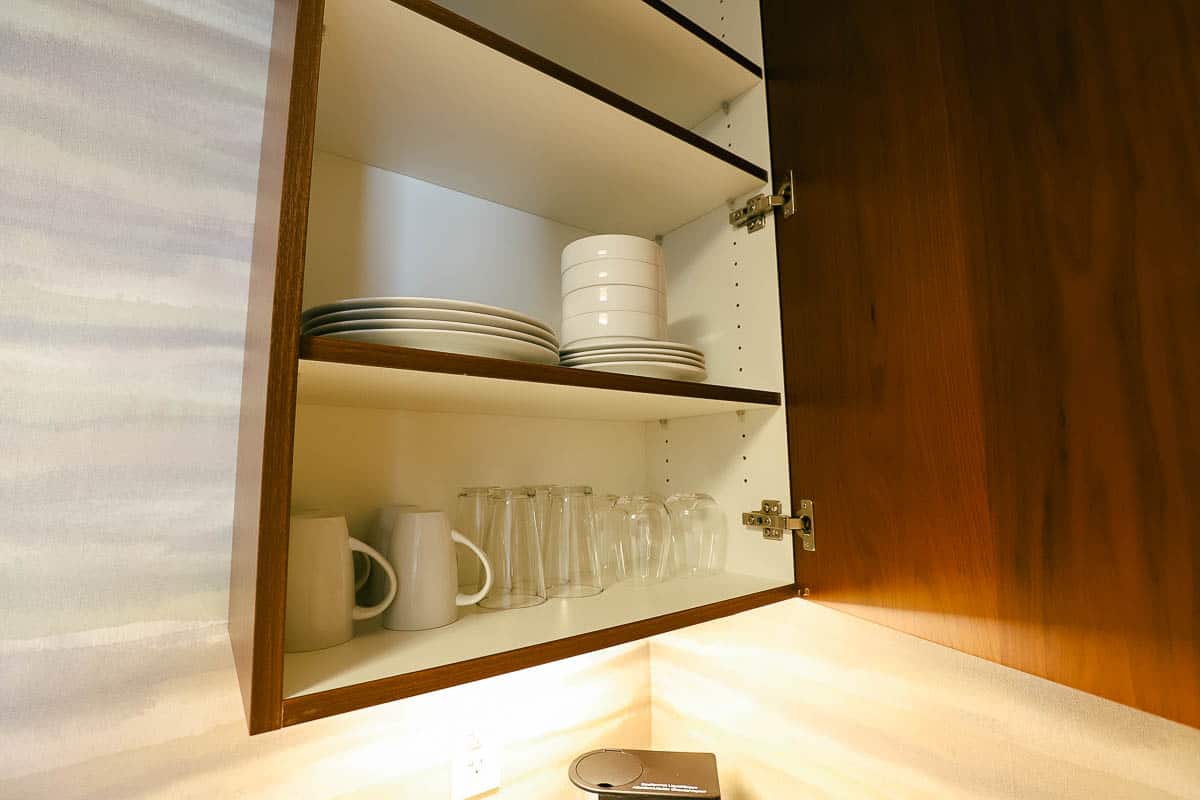 cabinet open to reveal dishes and glassware 