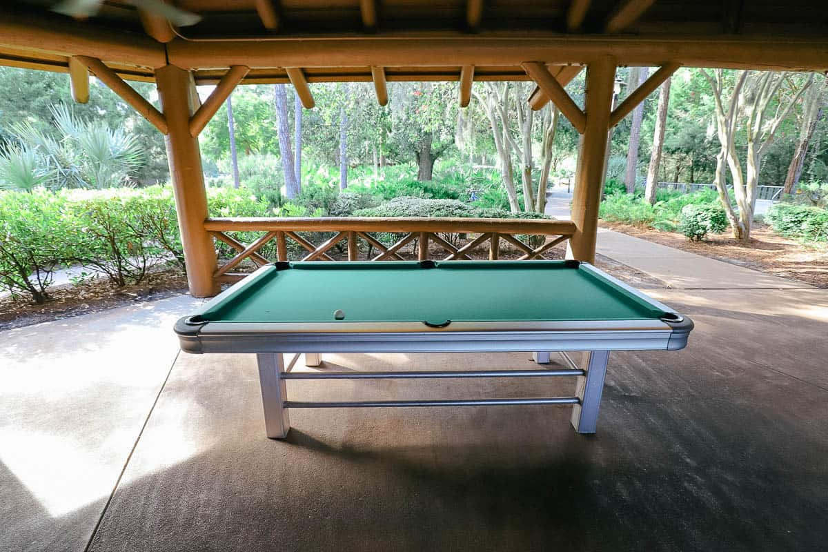 a recreational pool table under a covered pavilion by the pool 