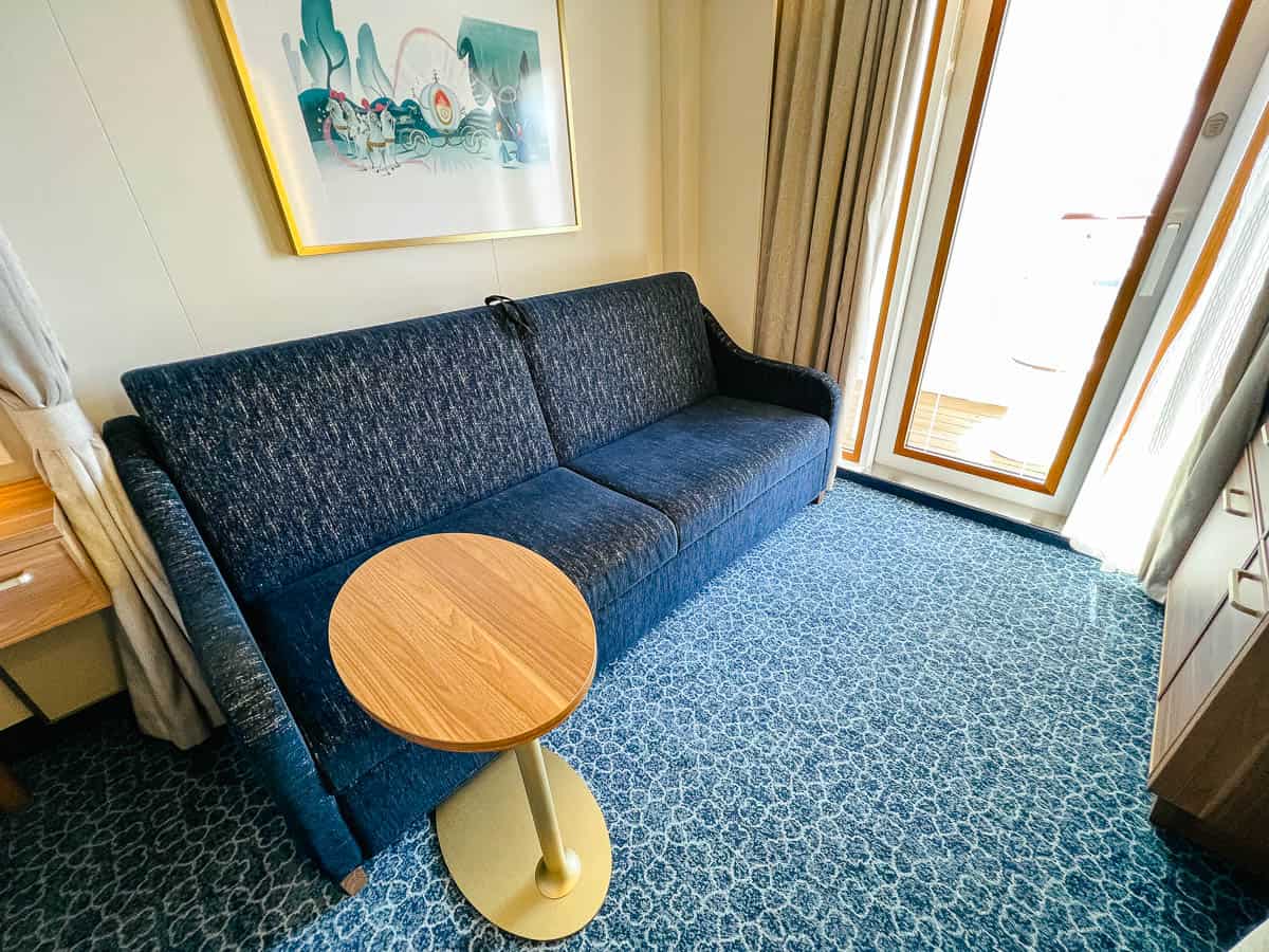 a sofa with a small table in Disney Wish stateroom 