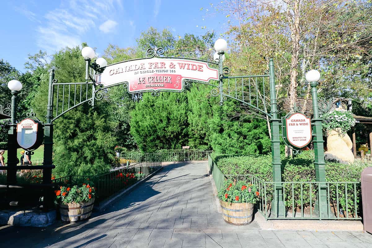 the entrance to Canada Pavilion at Epcot with signs for the attraction and dining 