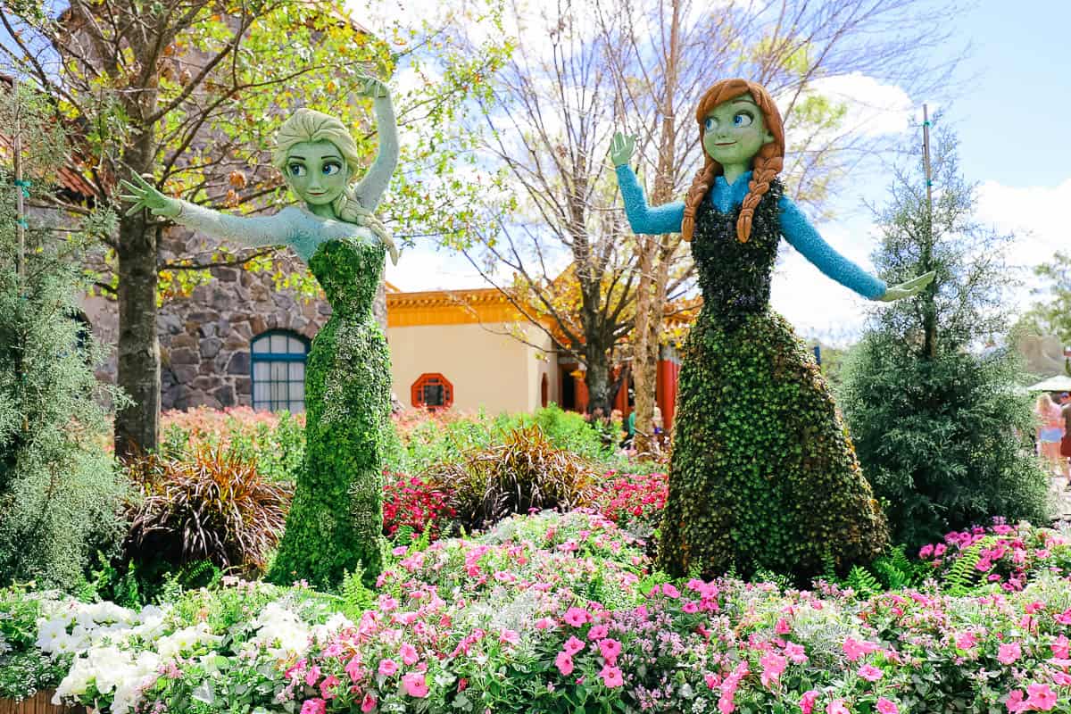 Anna and Elsa character topiaries surrounded by flowers 