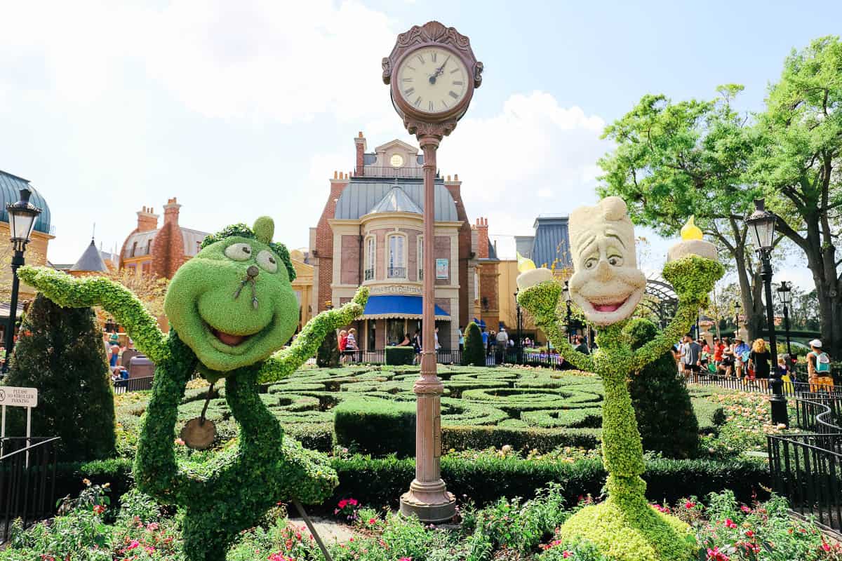 Lumiere and Cogsworth in front of Epcot's France Pavilion in topiary form