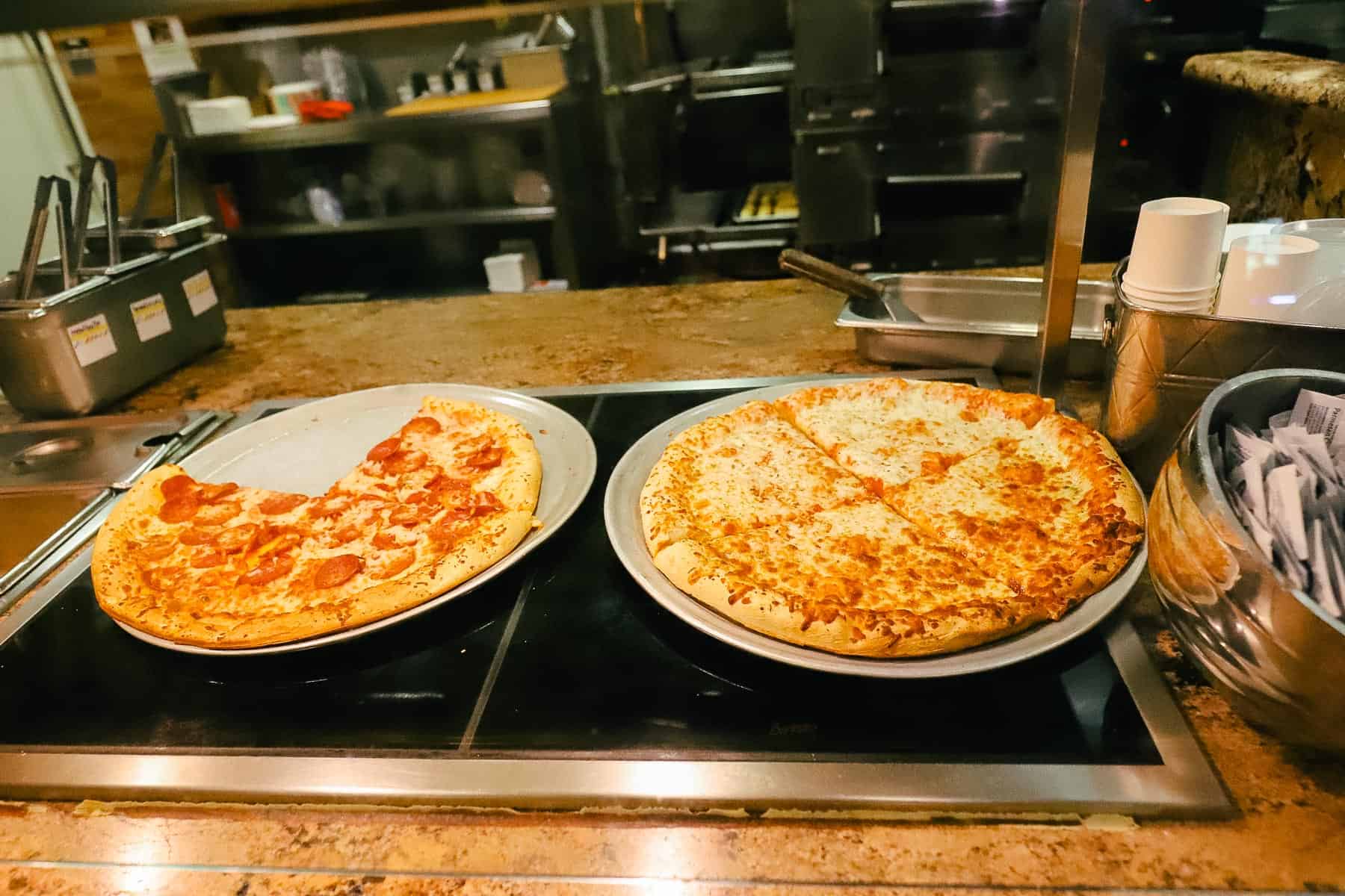 a station with a pepperoni pizza on the left and cheese pizza on the right 