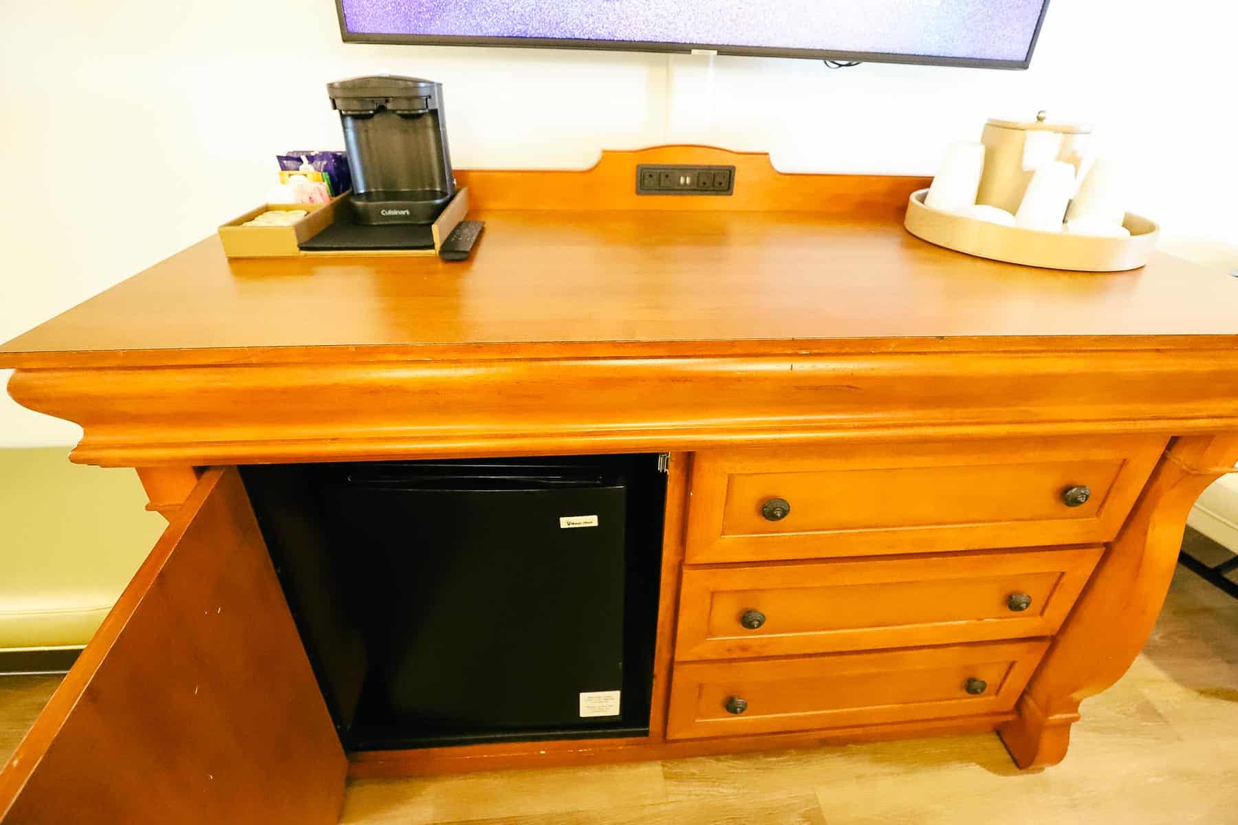 a dresser with a cabinet and a mini fridge and  three drawers on the opposite side 
