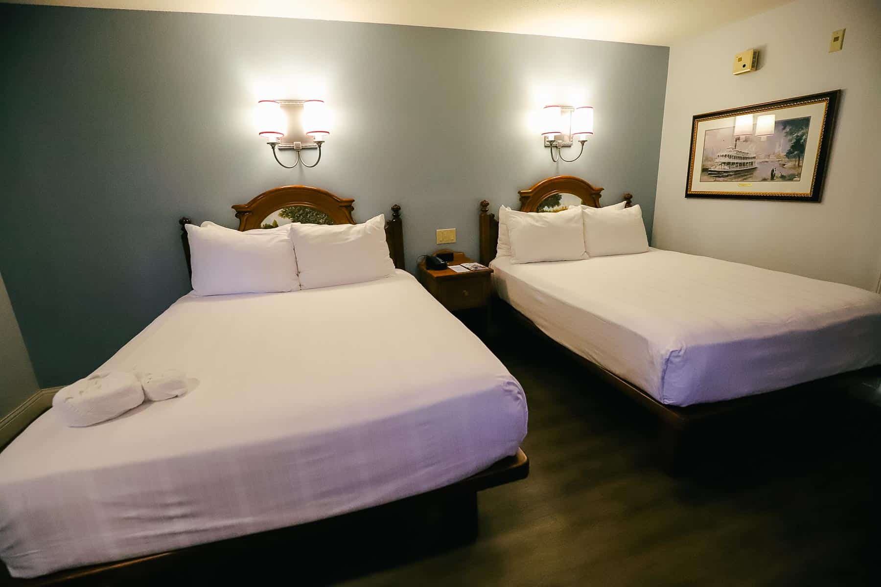 two queen beds with layers of white sheets and four pillows each 