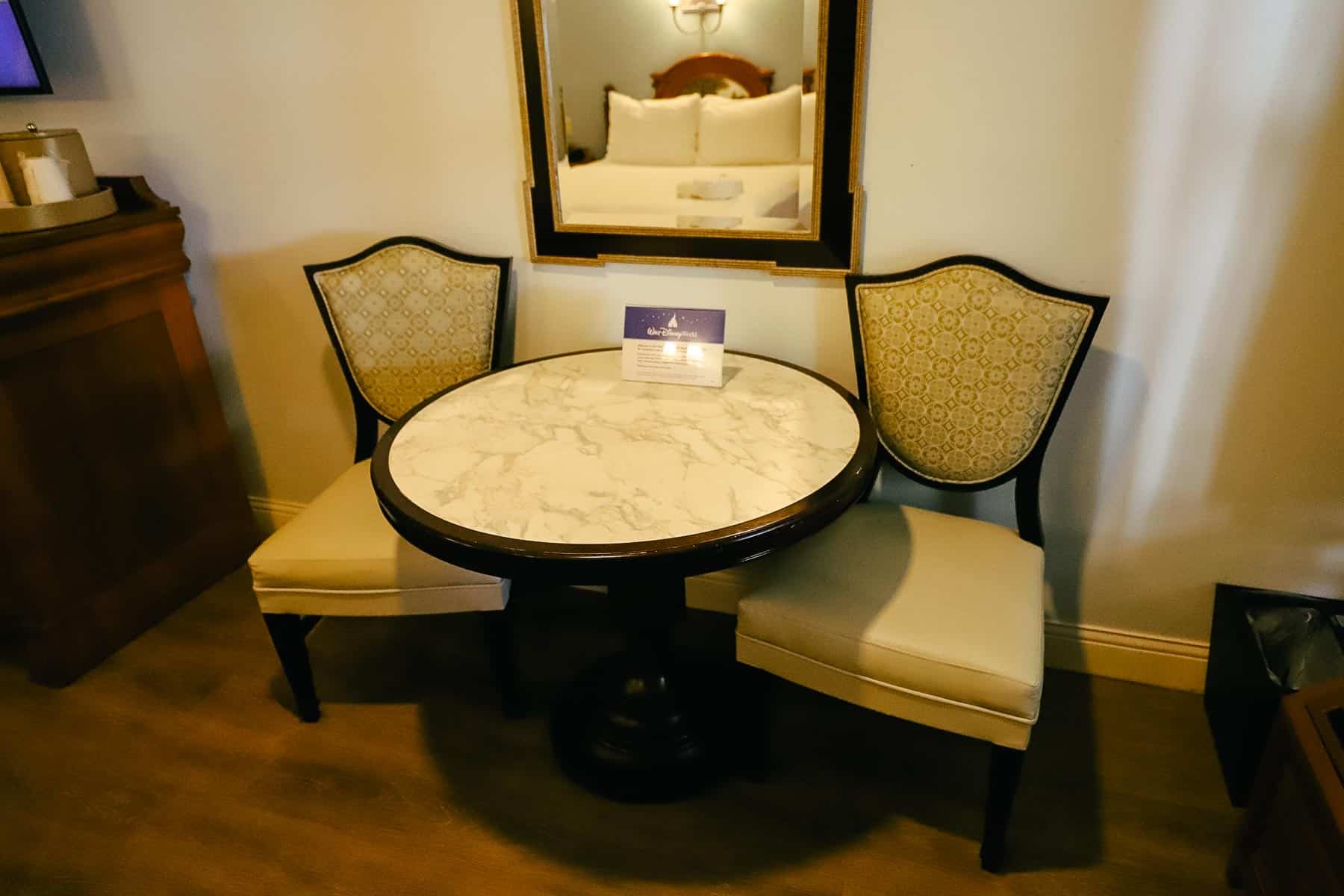 a table with a marble top and two chairs in the front corner of the room