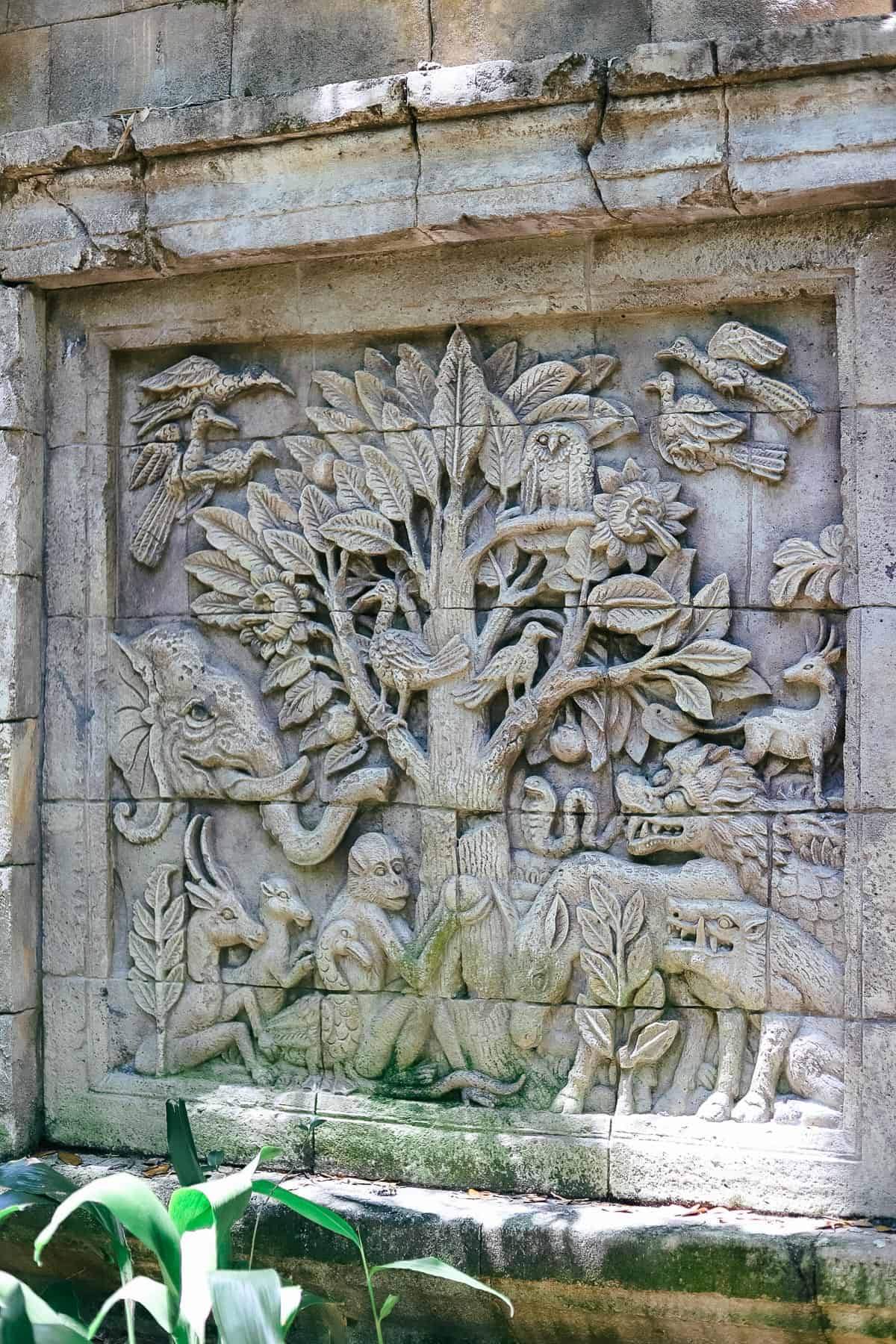 a wall with designs featuring animals around a tree 