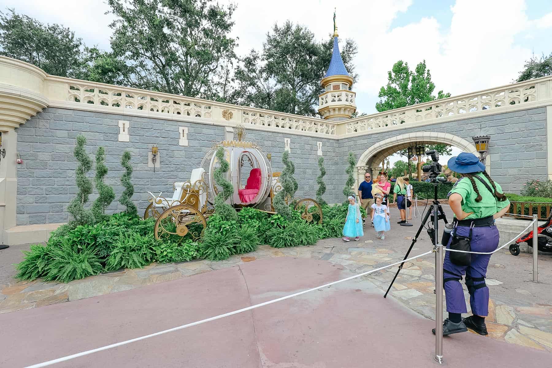 a PhotoPass photographer takes photos of families in front of Cinderella's coach on the 4th of July 