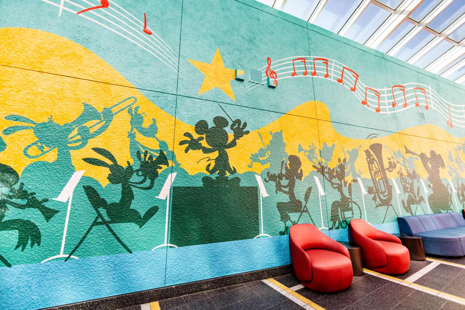 a mural in yellow, green and red featuring silhouettes of Disney characters playing musical instruments 