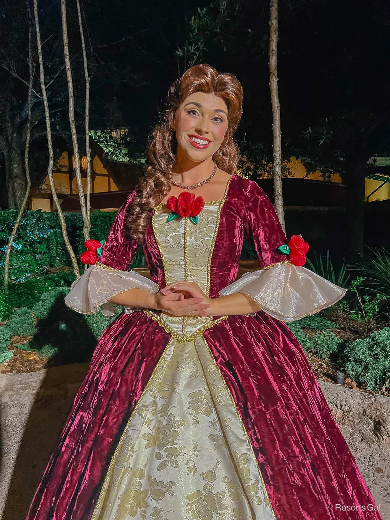 Belle in holiday red gown with gold detailing and roses. 