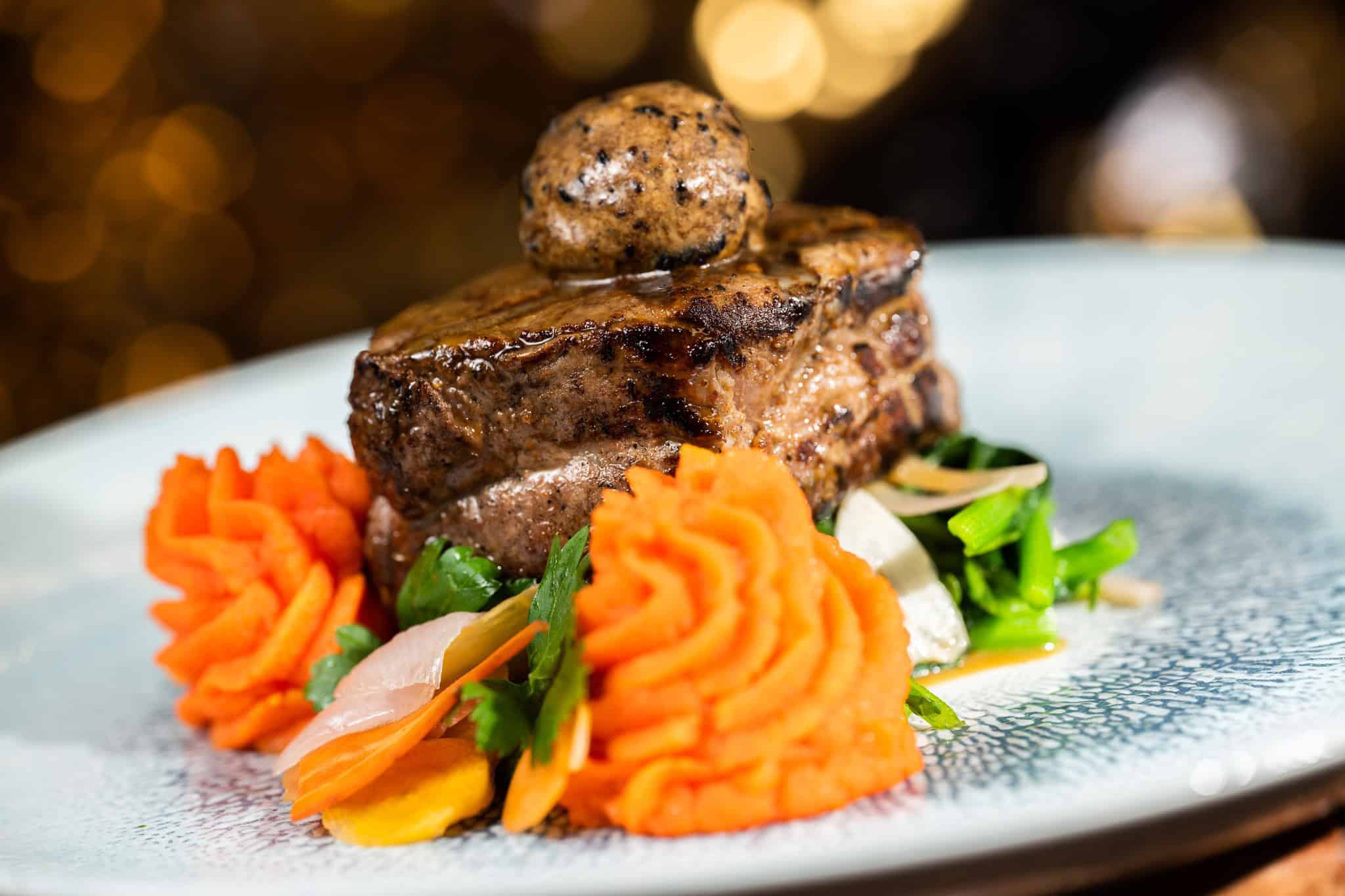 Filet Mignon on top of an orange carrot mash 