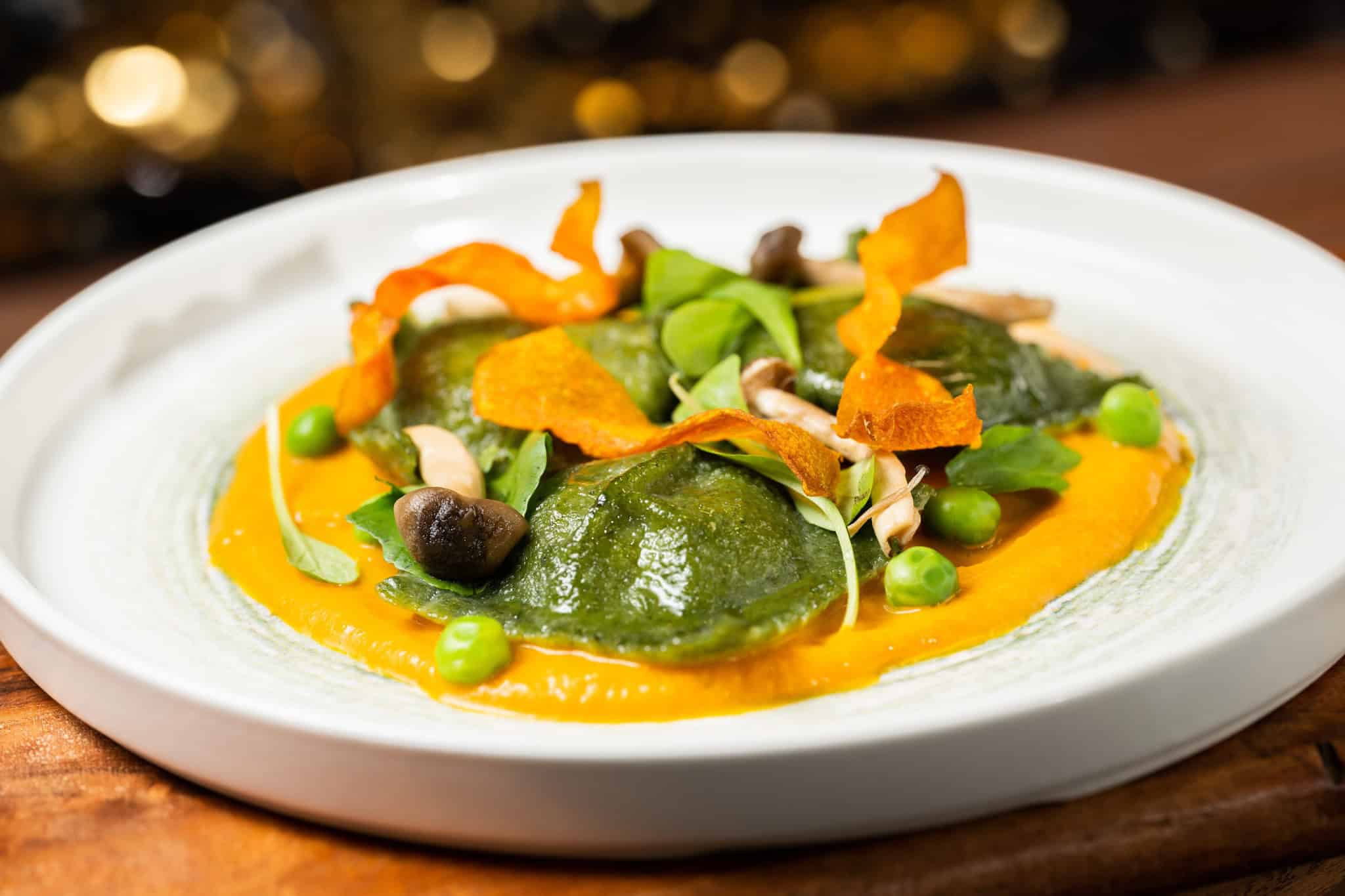 House made ravioli with carrot puree and toped with English peas 