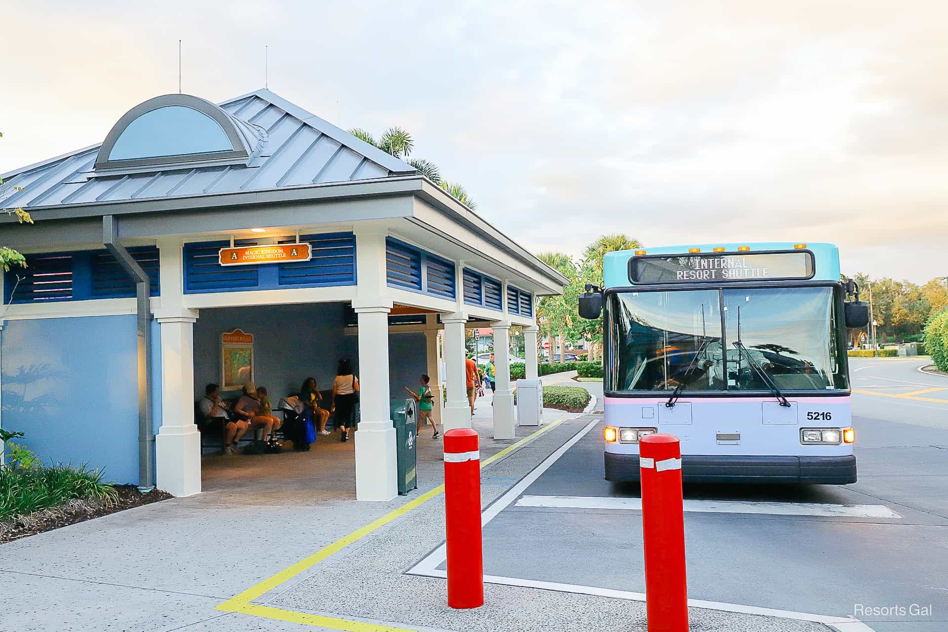 a purple bus waits at a bus stop that has internal resort shuttle as its destination 