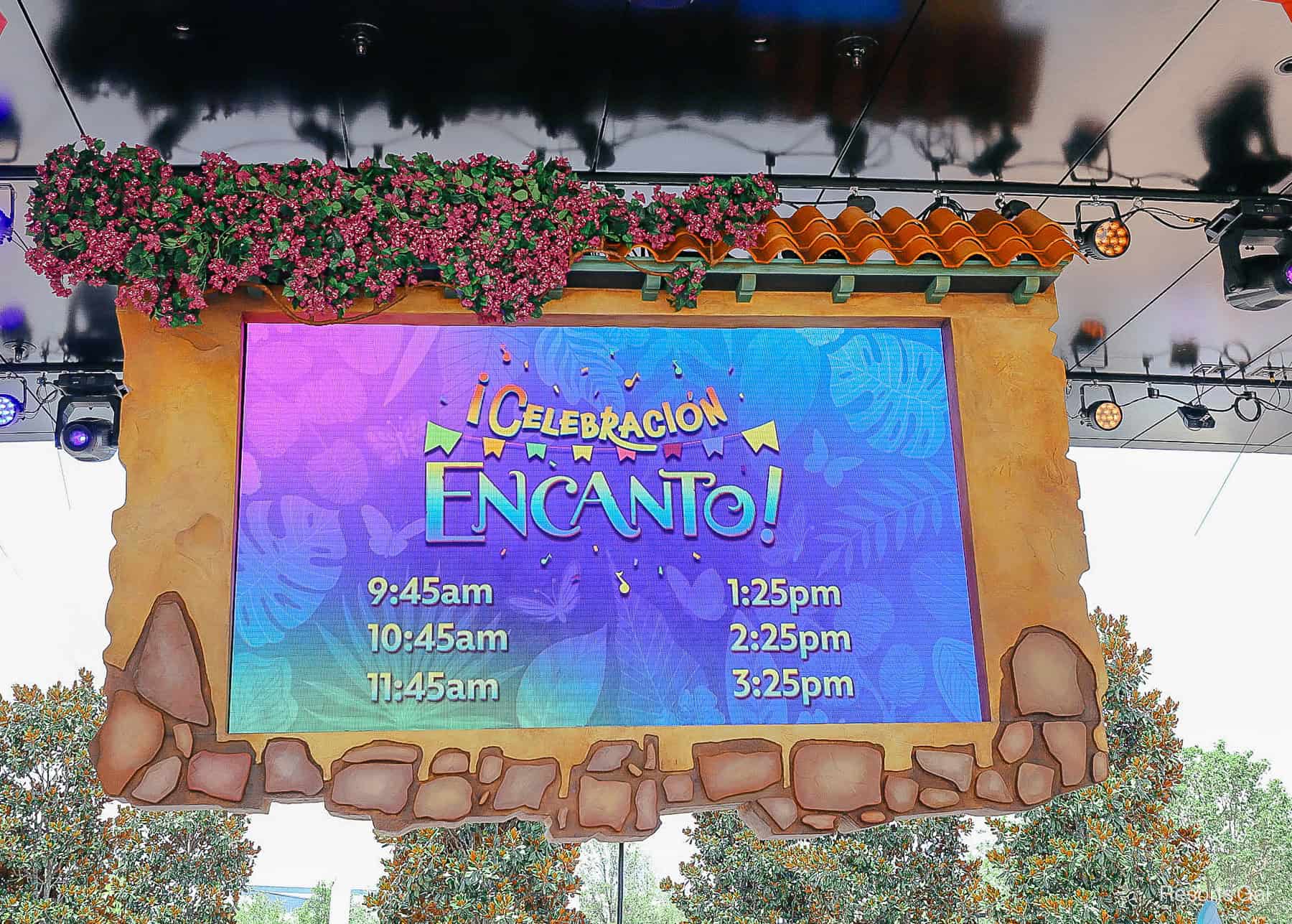 ‘¡Celebración Encanto!’  showtimes listed on a screen over the stage 