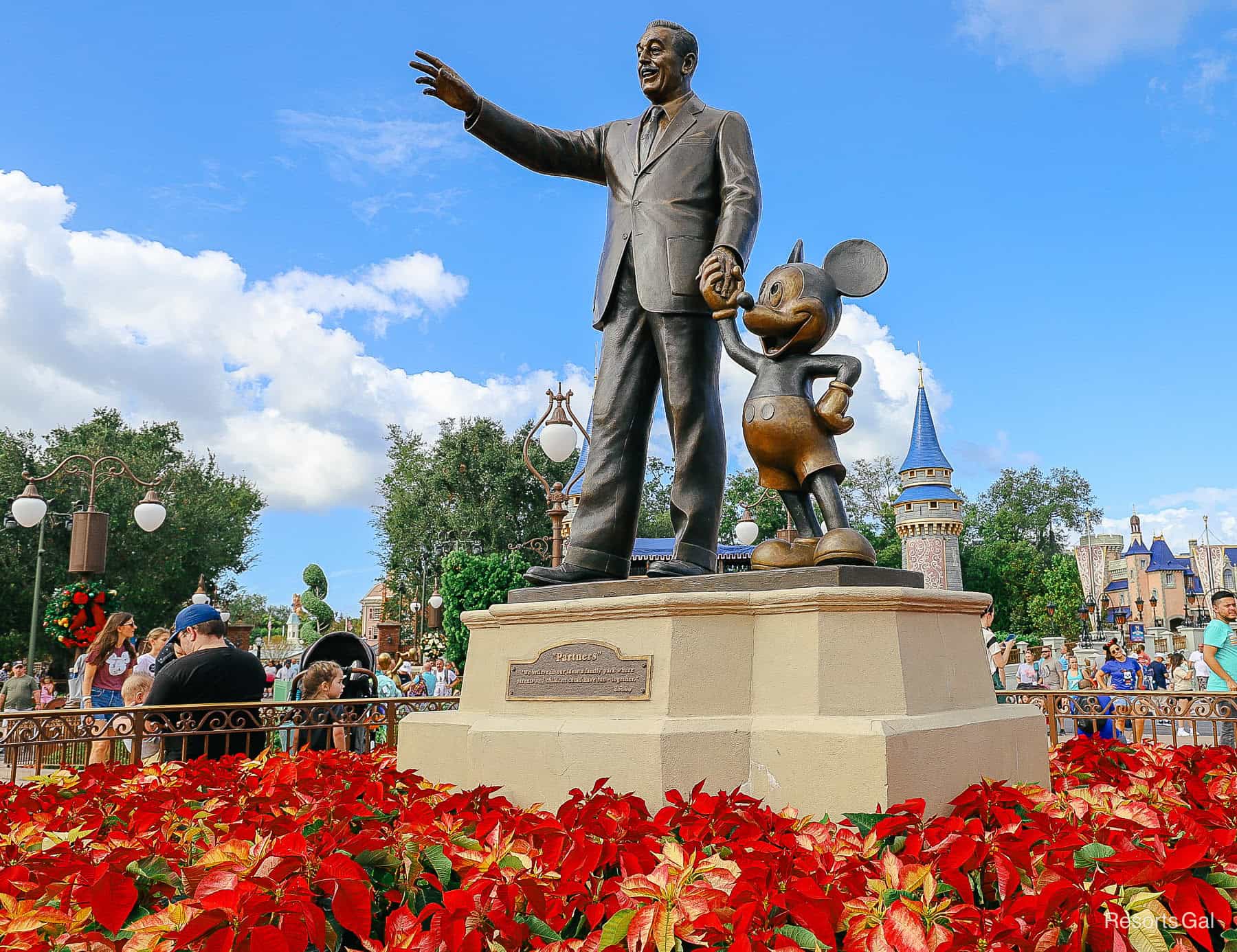 Partners Statue during Christmas at Magic Kingdom with poinsettias surrounding it 