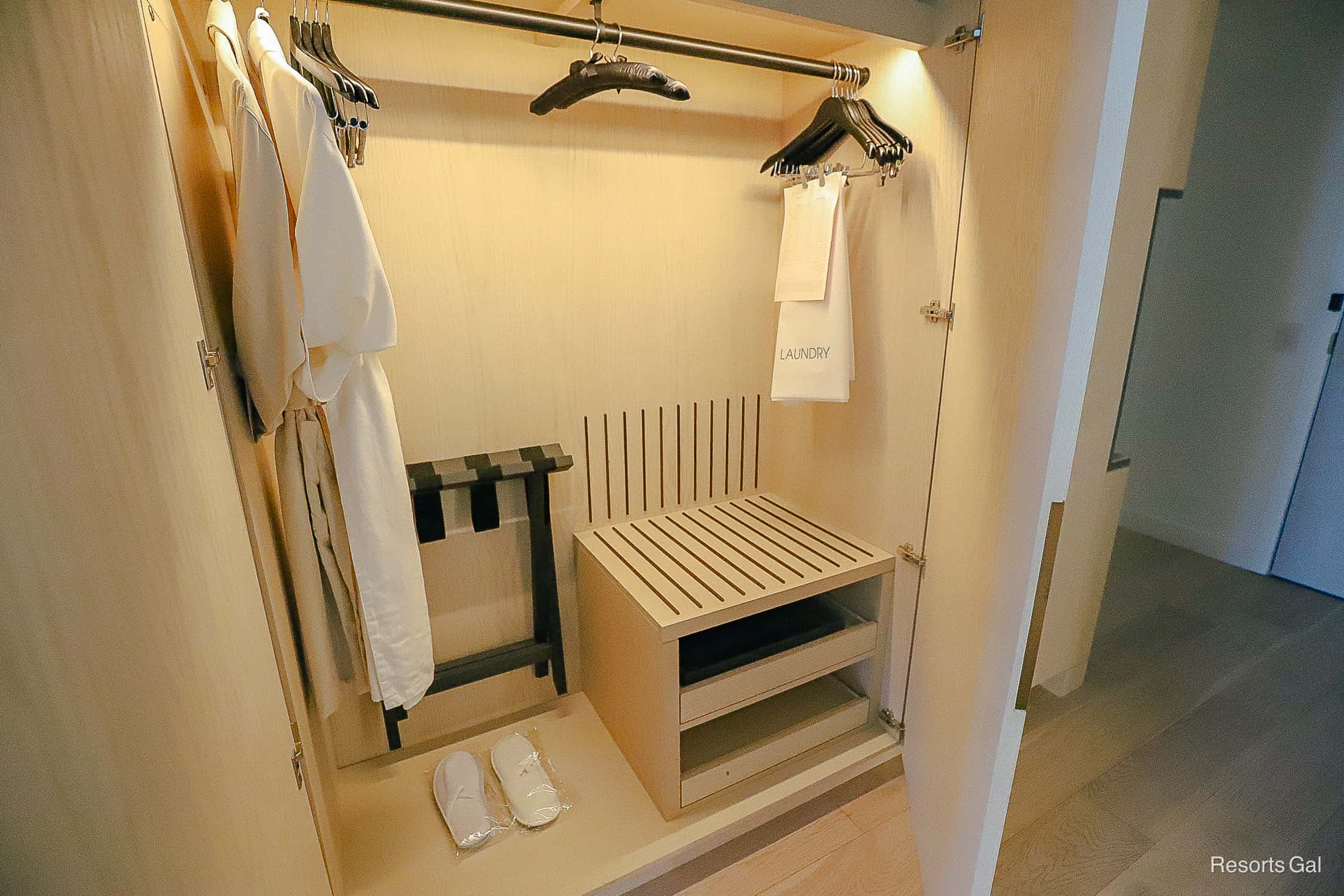 a closet with wooden hangers, two robes, slippers and satin hangers 