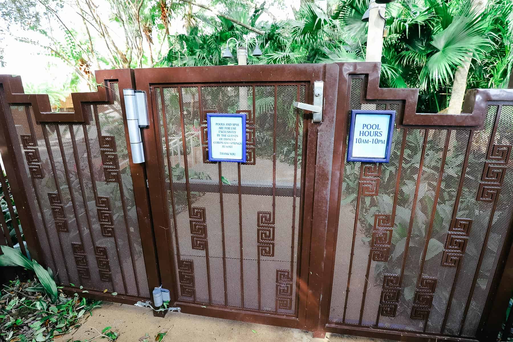 a gate with a sign that says the pool is for guests of Coronado Springs only and lists the pool hours 