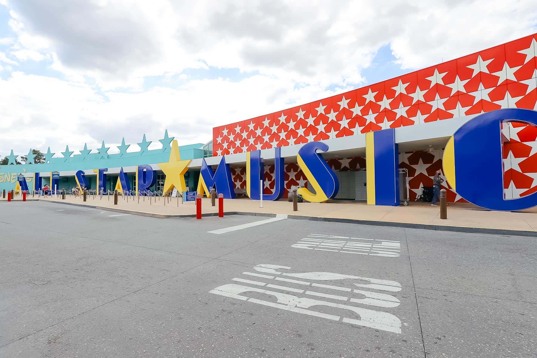 the entrance to All-Star Music with large letters spelling out the resort's name in blue and yellow with red and white star backdrop 