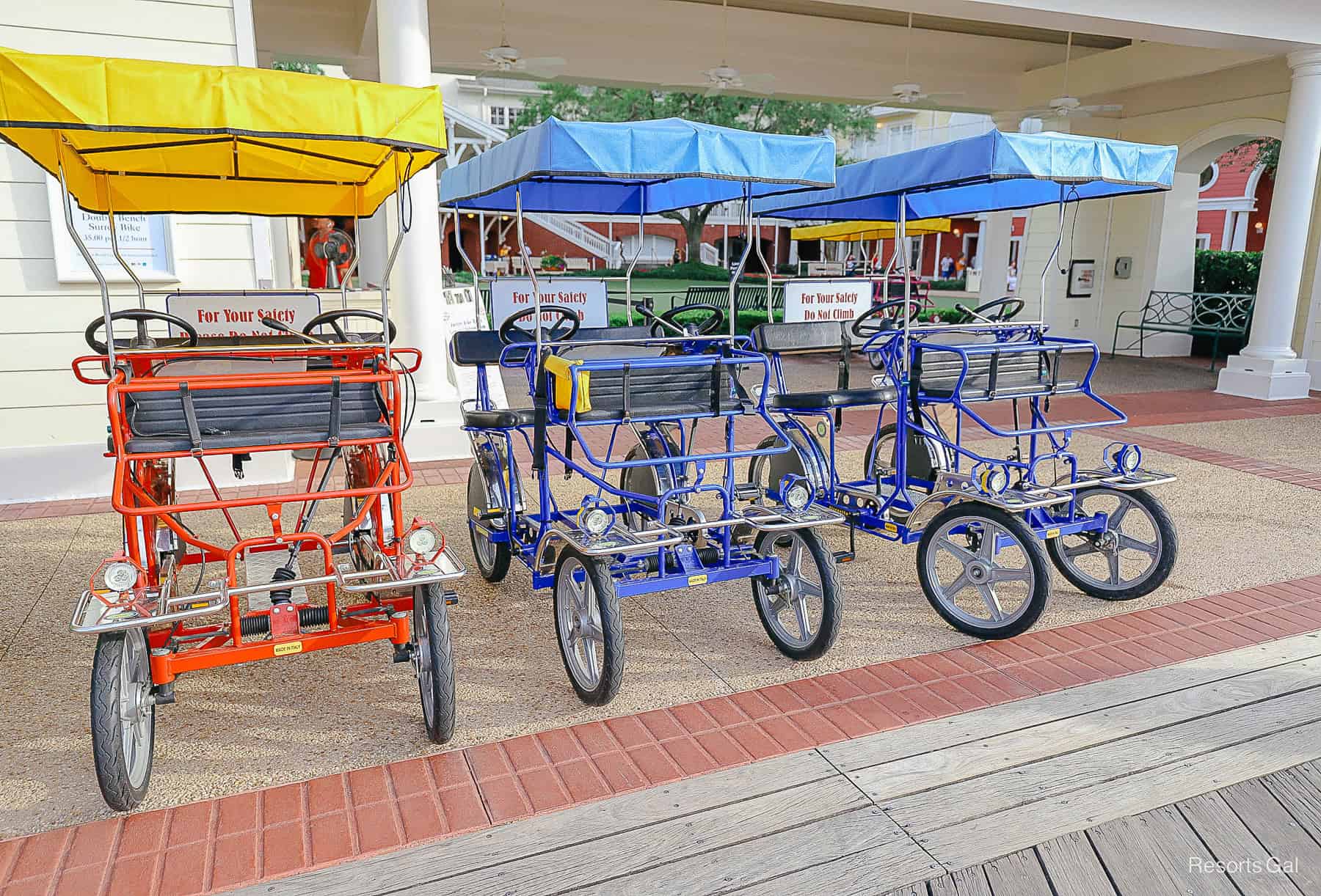 a red and two blue Surrey bikes parked at Disney's Boardwalk 