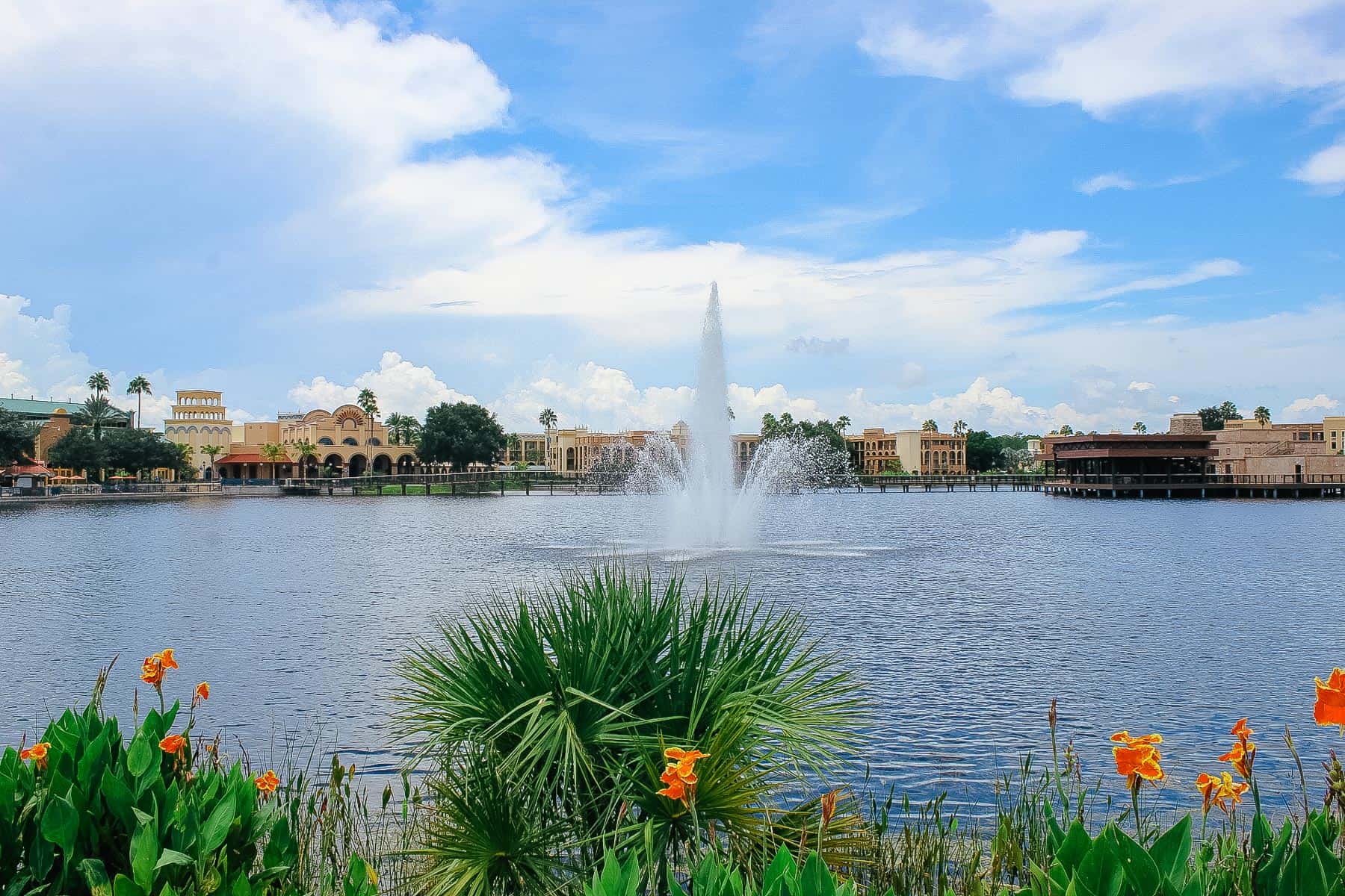 a view of Disney's Coronado Springs Resort with the lake and orange flowers blooming 