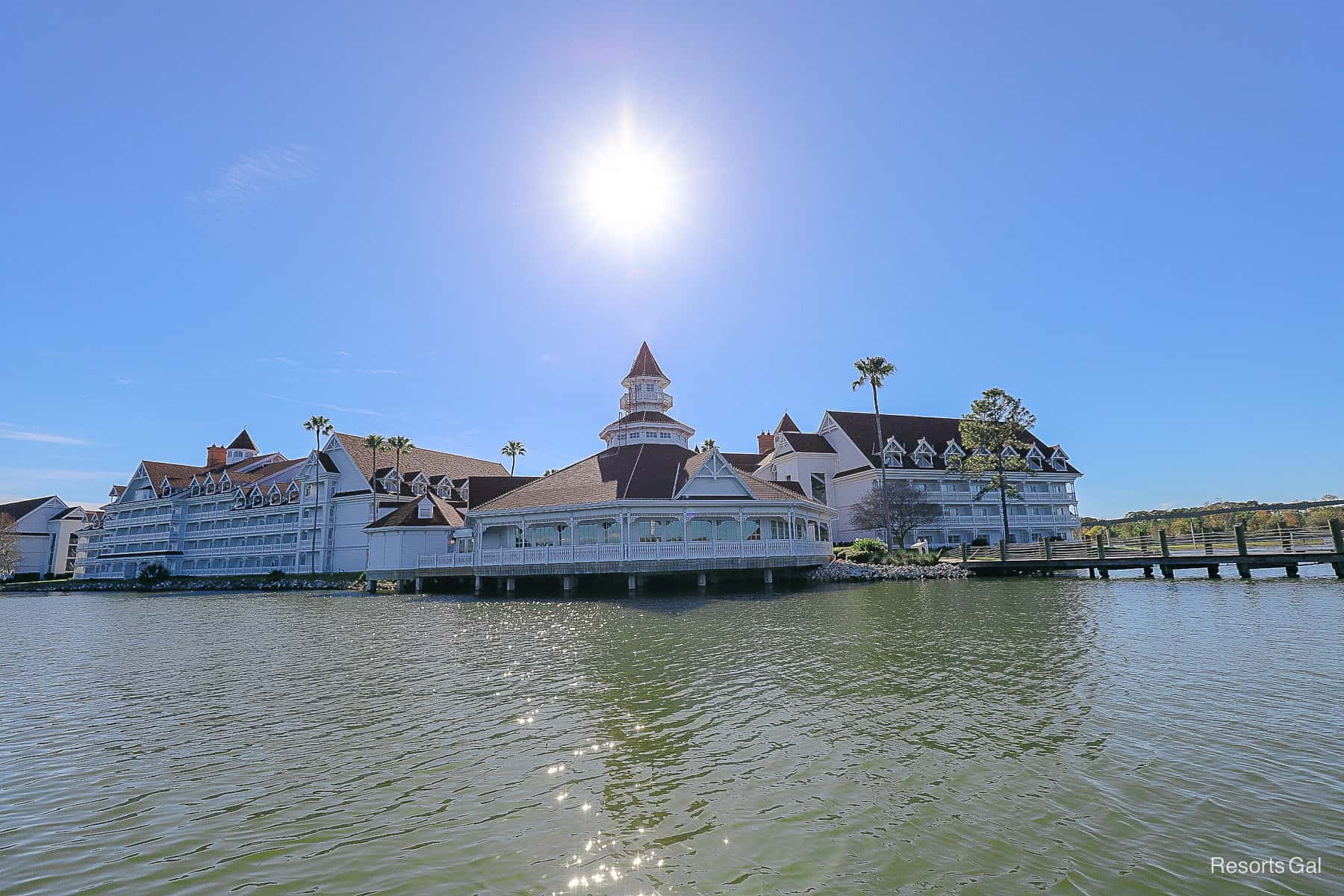 a view of the sun shining over the Grand Floridian taken from the water 