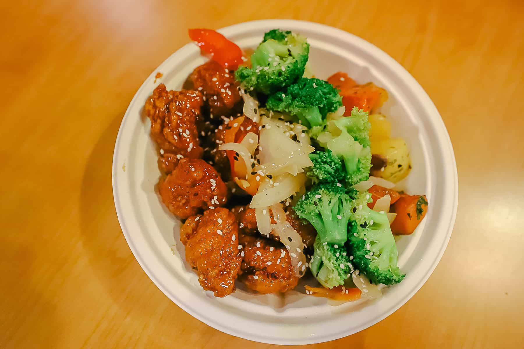 a bowl of sesame chicken with vegetables 