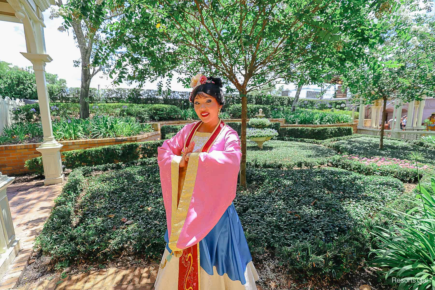 Mulan in her formal robes with pink, blue, and gold. 