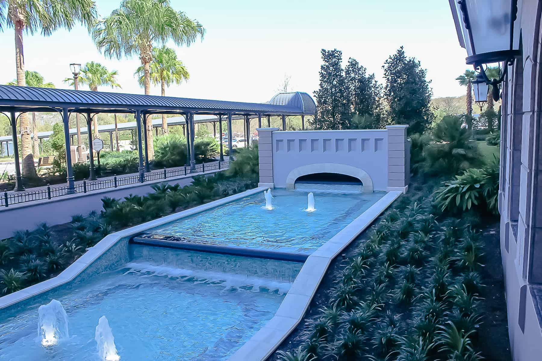 a fountain that runs adjacent to the walkway entering the resort