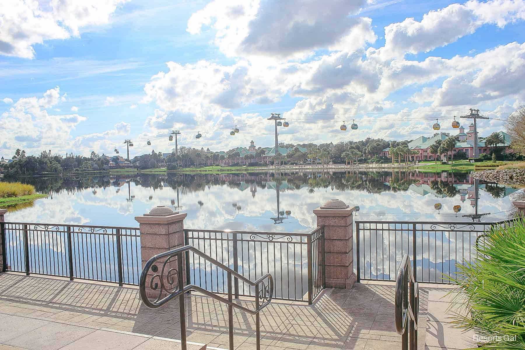 the Disney Skyliner travels by Caribbean Beach with its reflection in the lake 