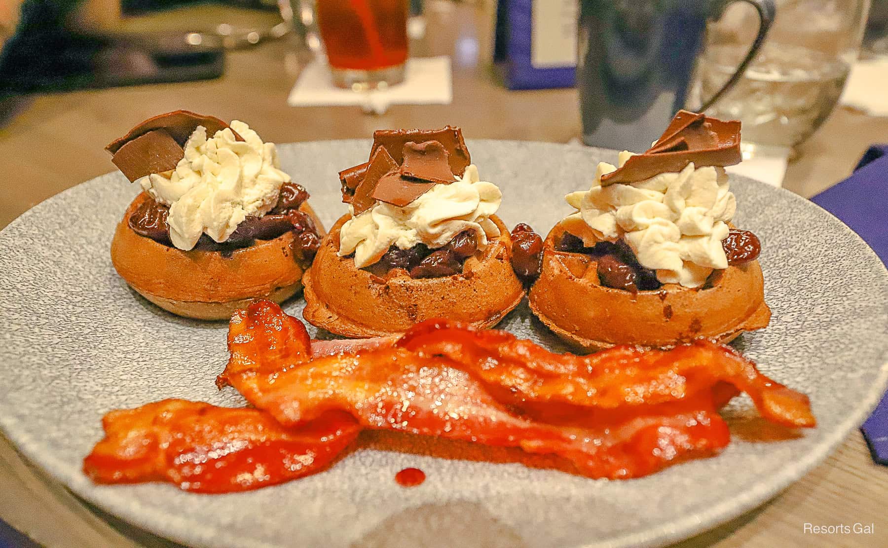 an order of chocolate waffles topped with whipped cream and a side of bacon from Ale and Compass Disney Hotel Restaurant 