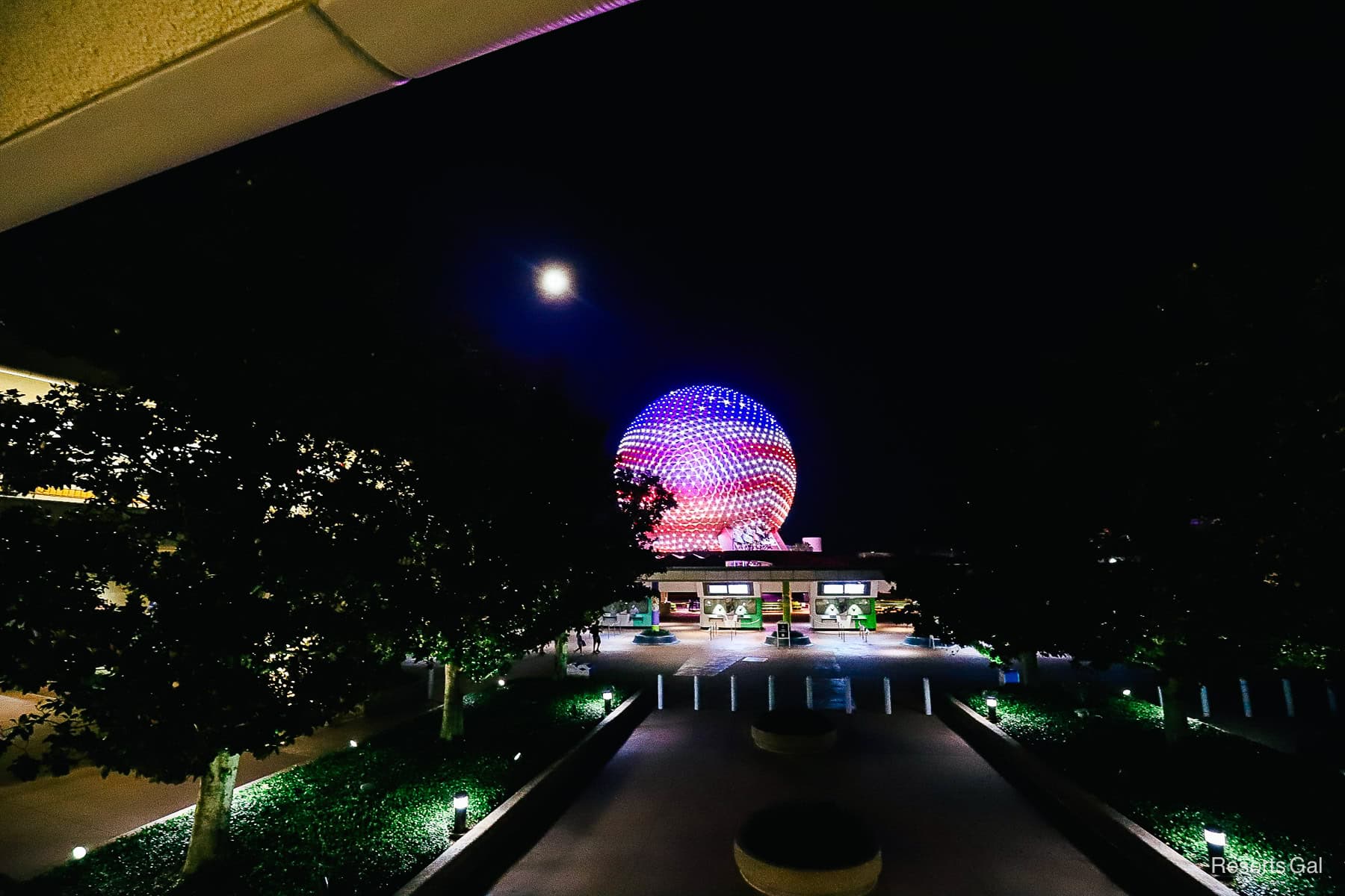 Spaceship Earth as seen from the monorail platform with red, white, and blue projection maps. 