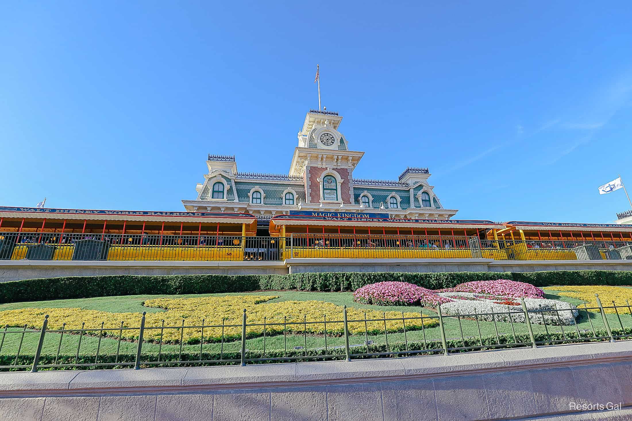 the entrance to Magic Kingdom with the train station in the background and Mickey floral planter 