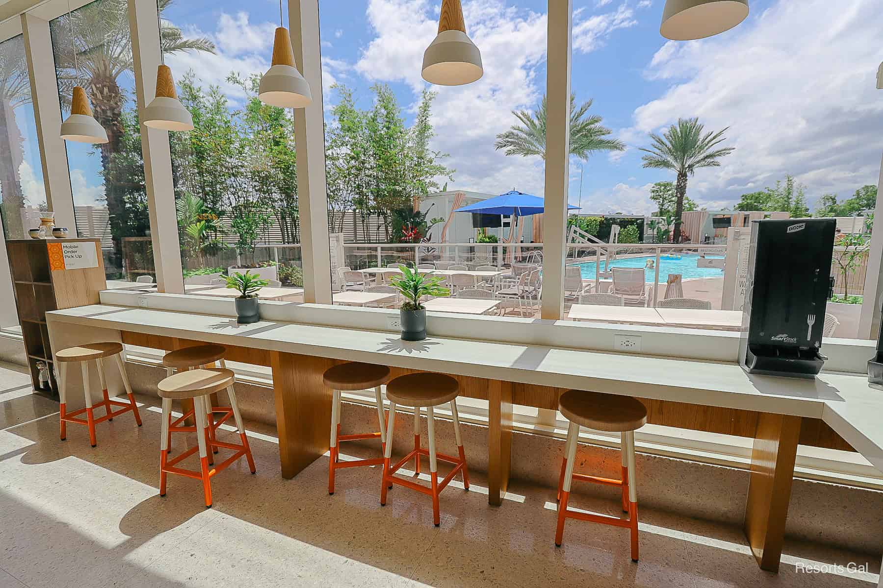 a bar with barstools against a window looking out to the pool 