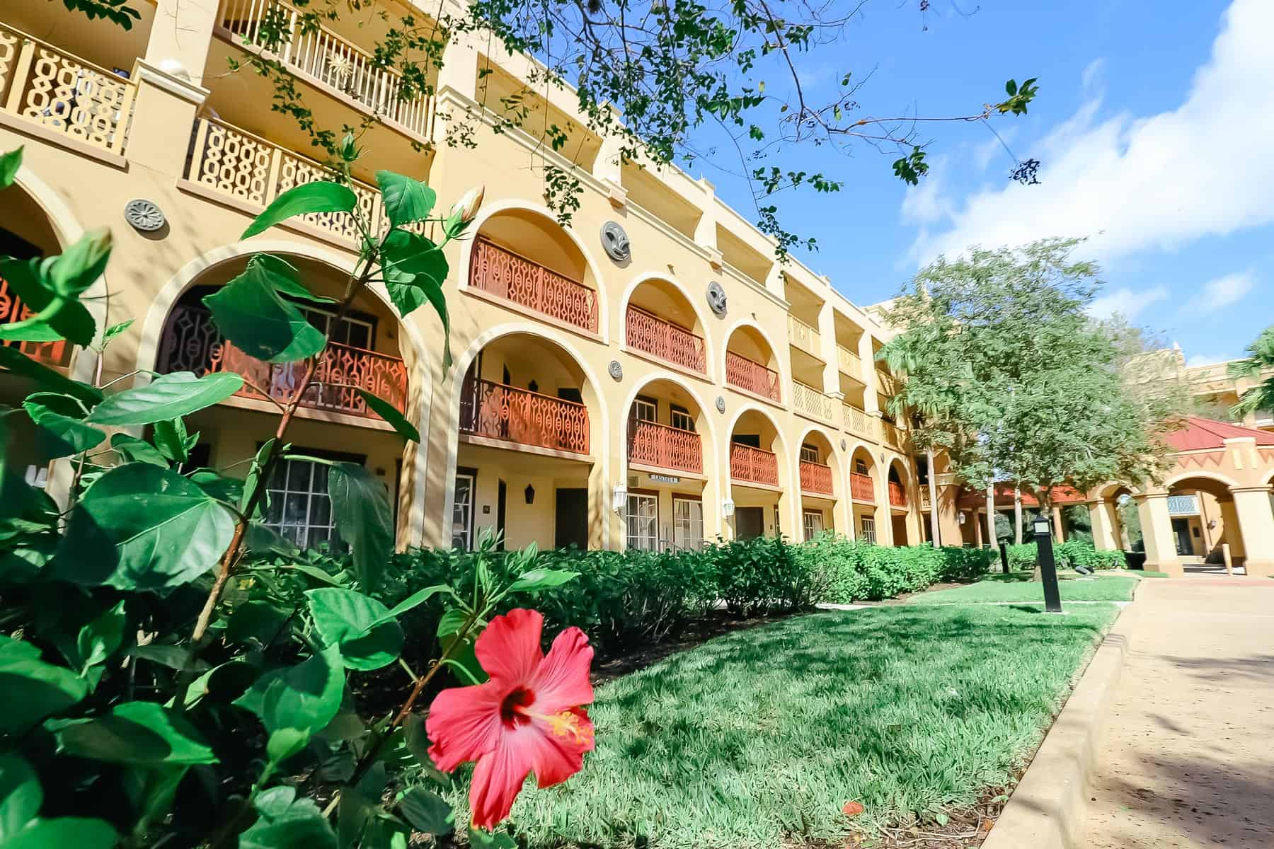 A golden building at Coronado Springs with red hibiscus in bloom 