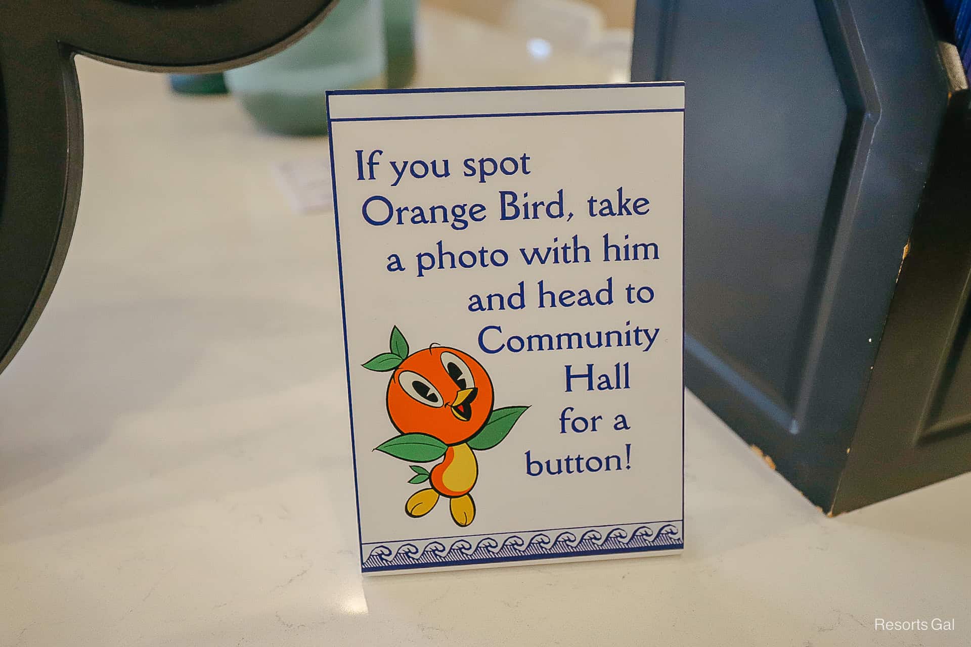 a sign with Orange Bird that says if you spot Orange Bird, take a photo with him and head to Community Hall for a button 