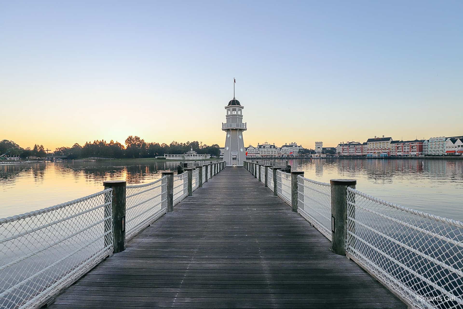 the lighthouse and boat dock with the sun first coming up behind it