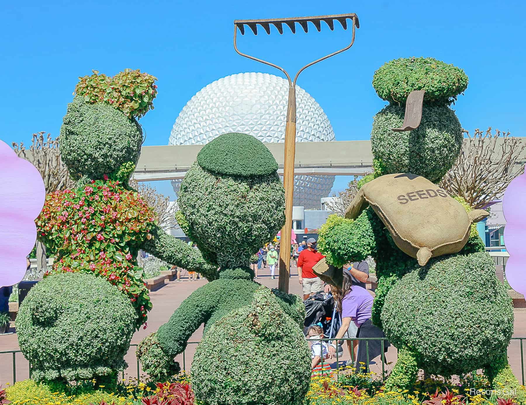 Donald Duck with Daisy and his nephew in topiary form with a view of Spaceship Earth