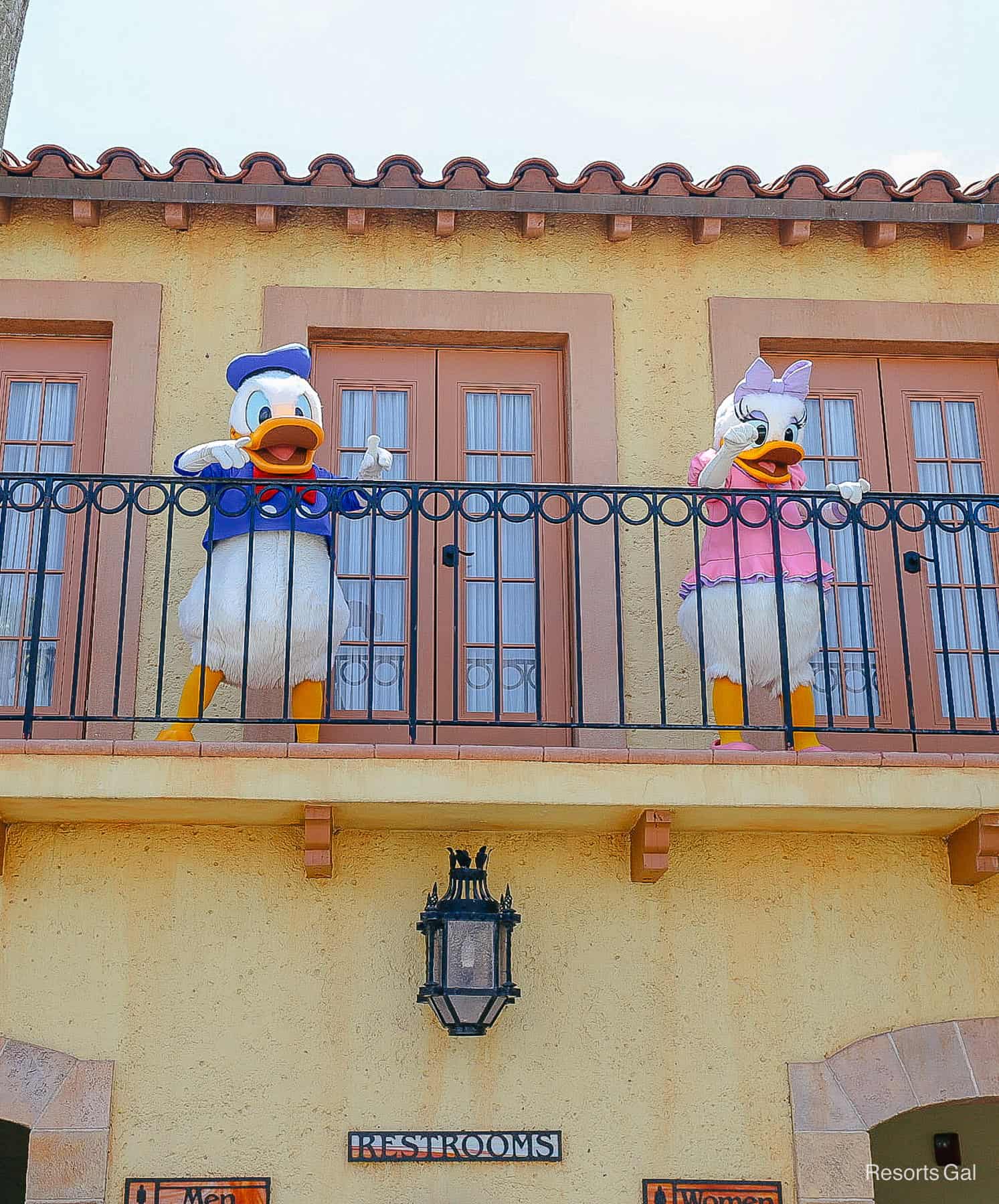 Donald and Daisy wave to guests from a balcony 