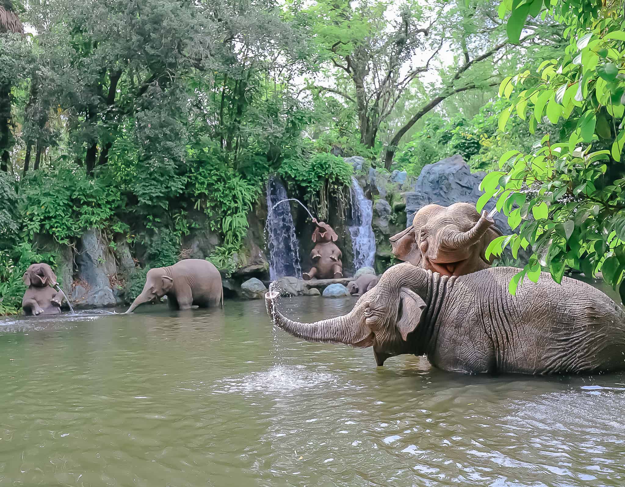 several animatronic elephants playing in the water of the Jungle Cruise