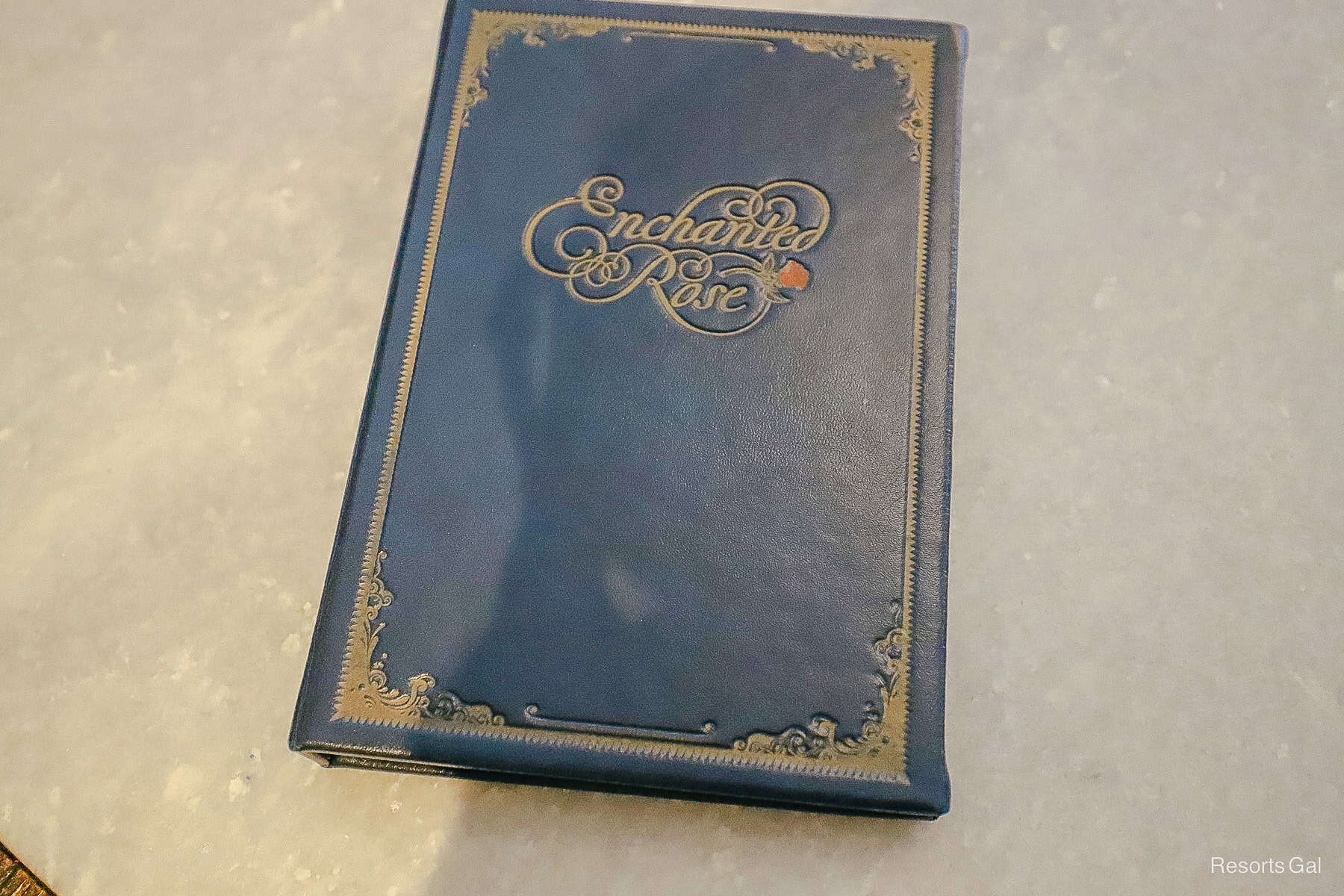 the menu cover in navy blue with gold trim and a red rose that says Enchanted Rose Lounge 