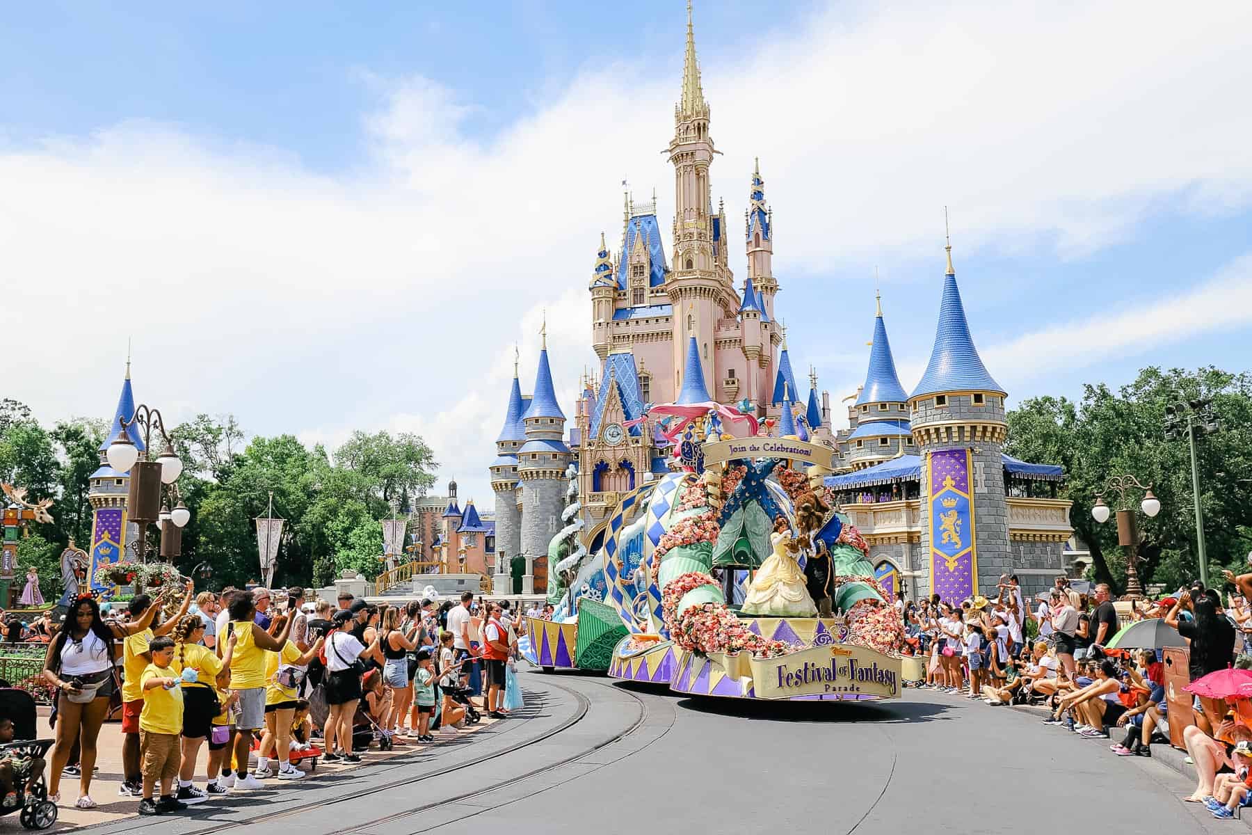 Beauty and the Beast at the front of the princess float as they pass Cinderella Castle on the Festival of Fantasy Parade Route. 