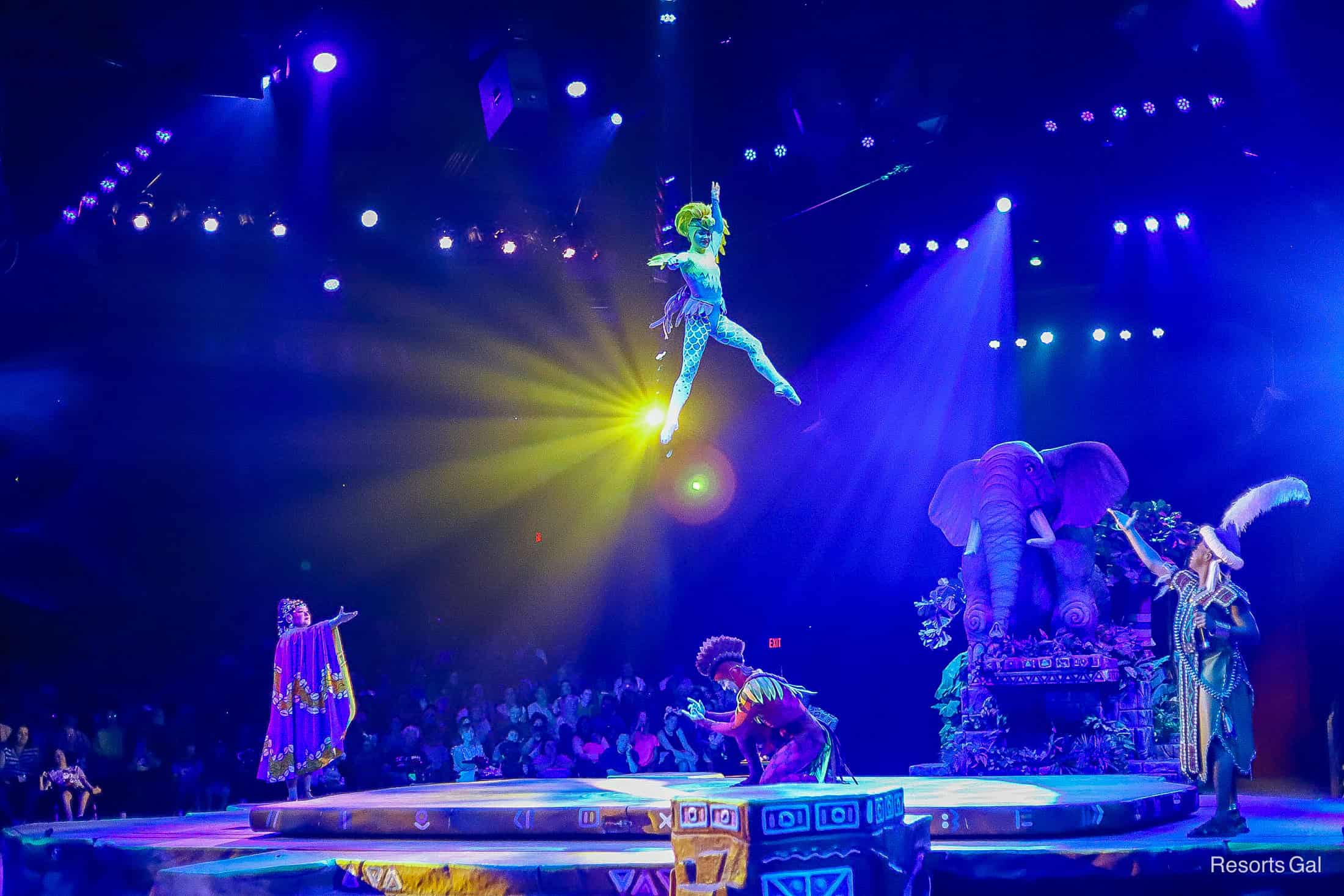 the aerial performer hangs from the ceiling high above everyone 