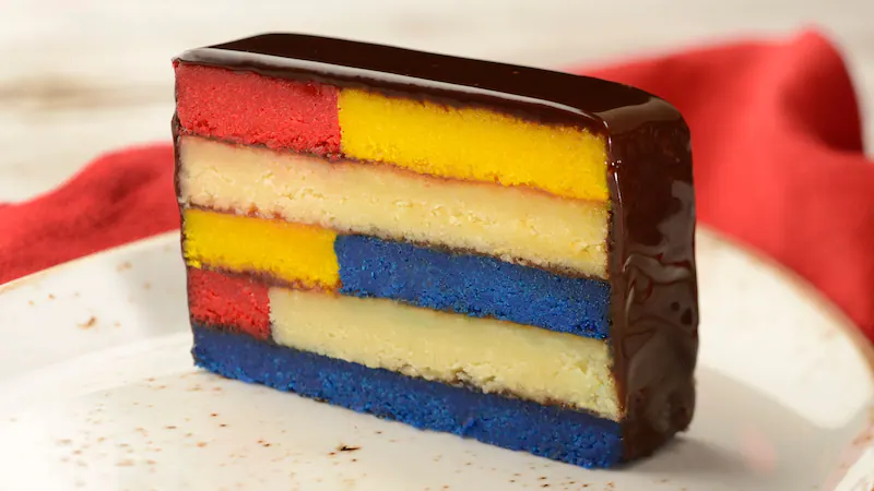 a cake with individual squares in yellow, blue, and red with chocolate icing 