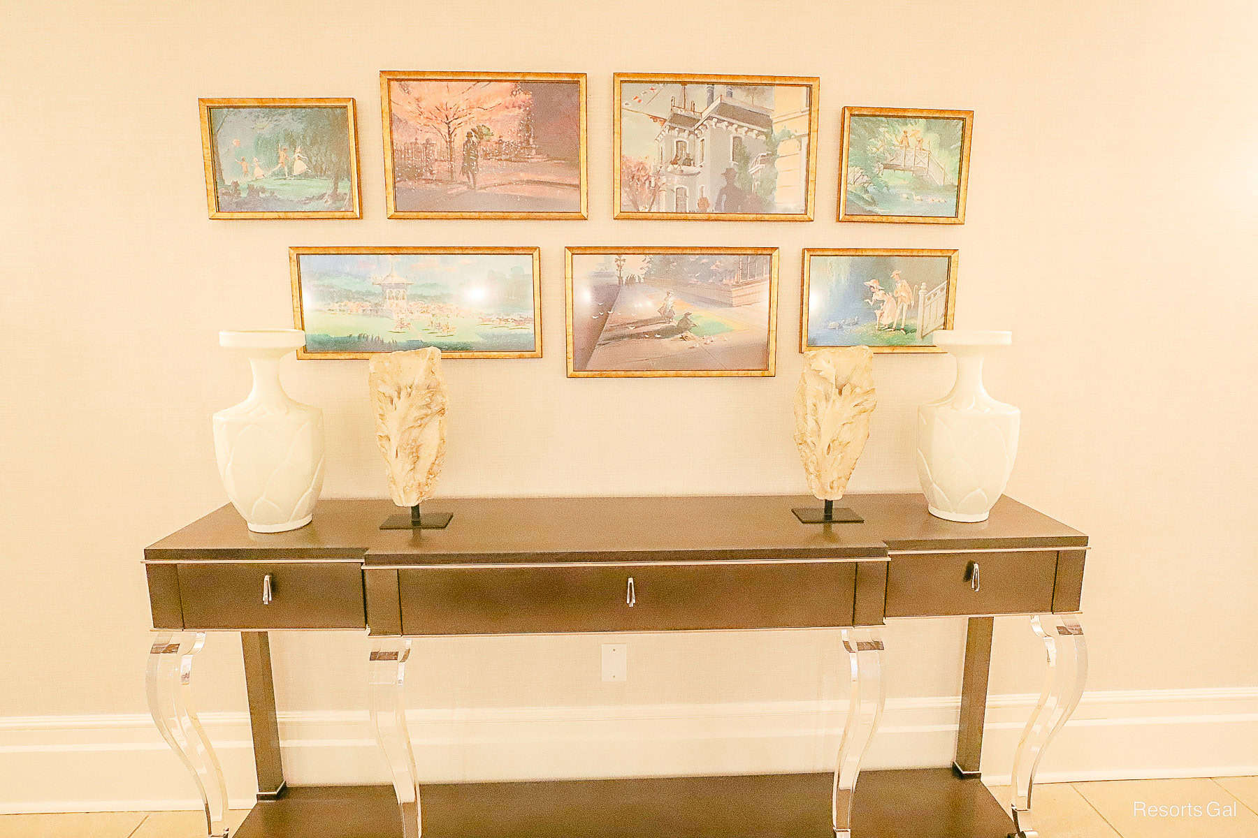 a sofa table with various miniature paintings above it