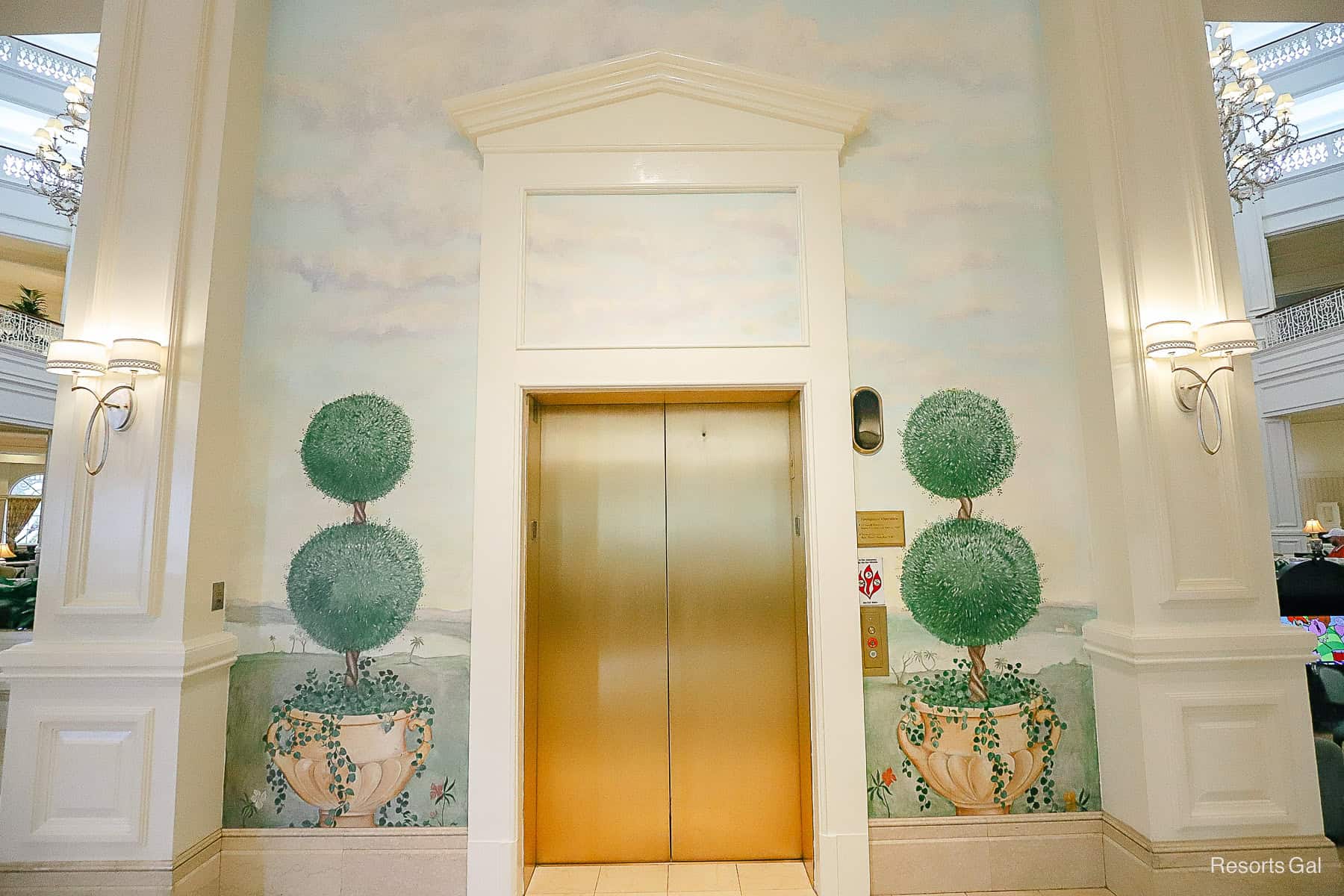 elevator mural closeup with topiaries in pots on each side of the gold doors 