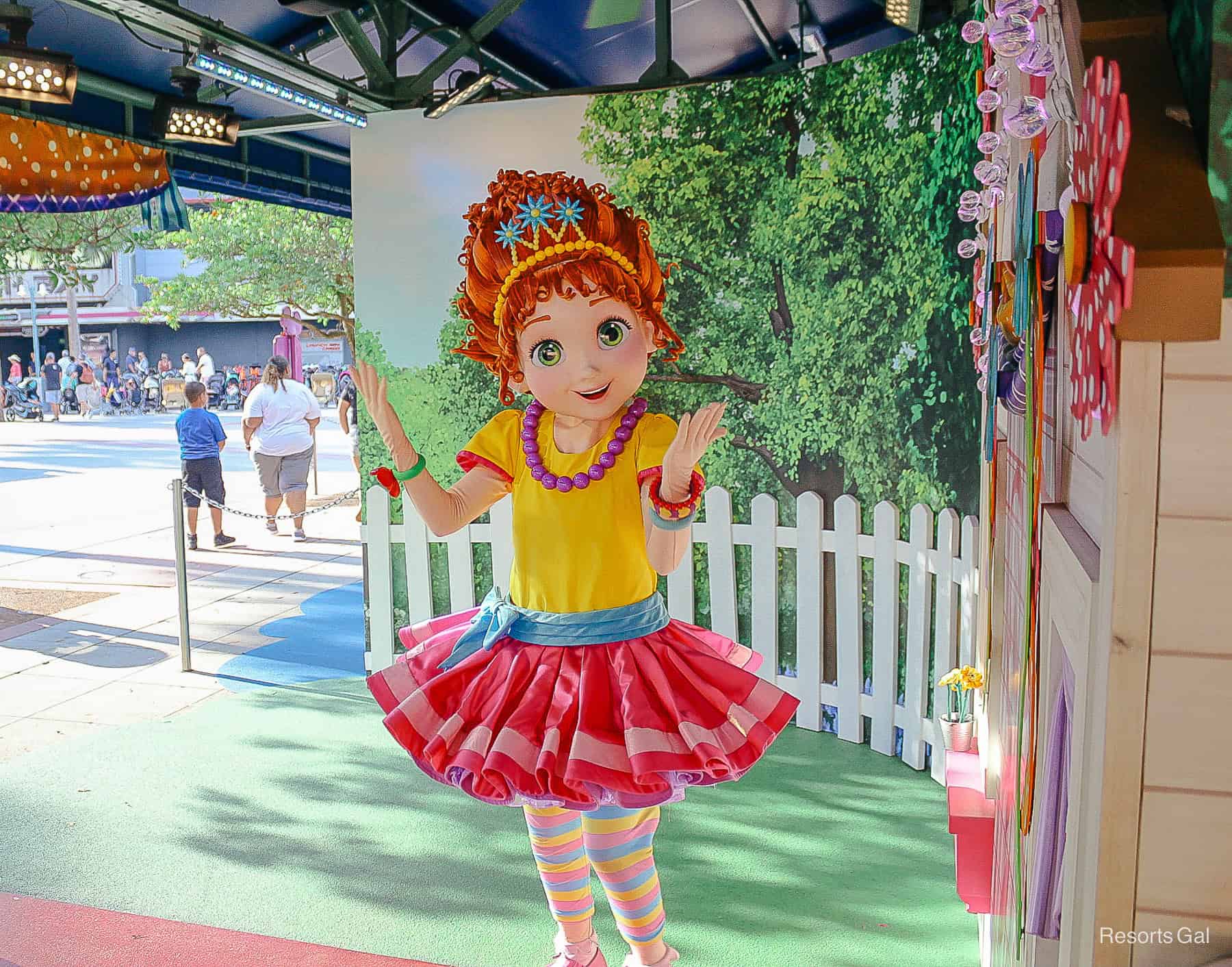 Fancy Nancy smiles in her bright yellow and pink dress at Disney's Hollywood Studios. 