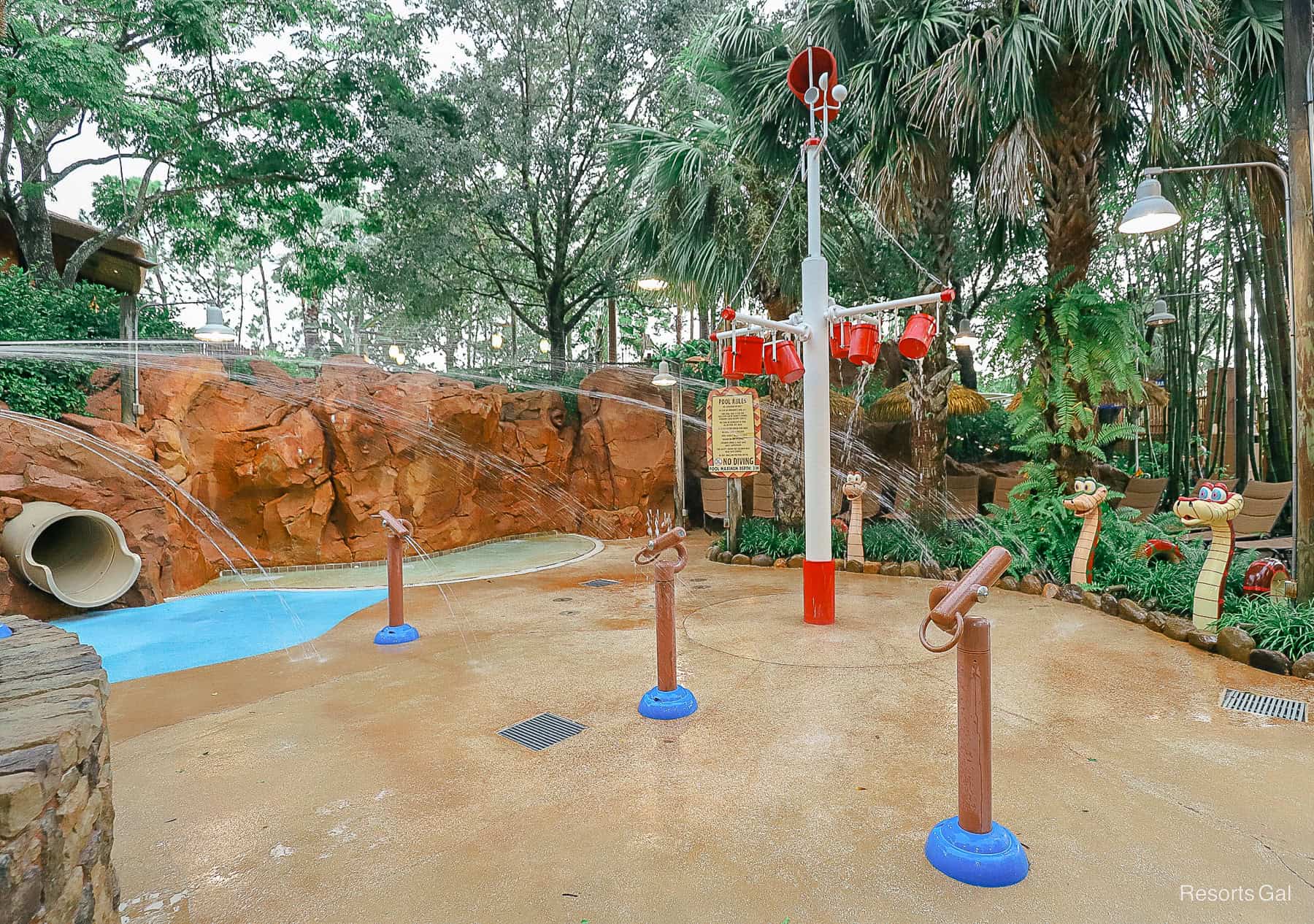 a children's splash pad area with sprayers and buckets of water 